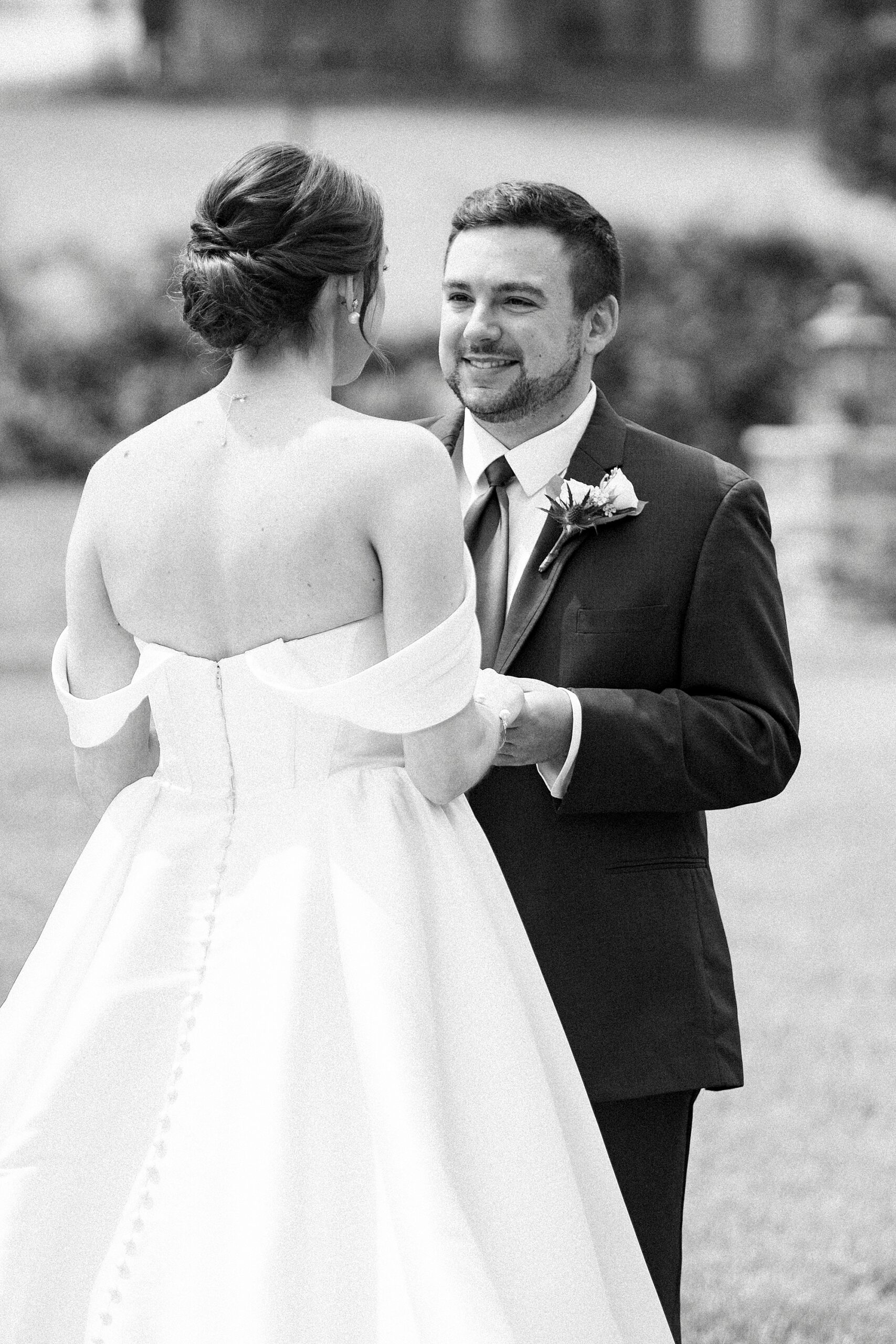 bride and groom hold hands during first look on lawn