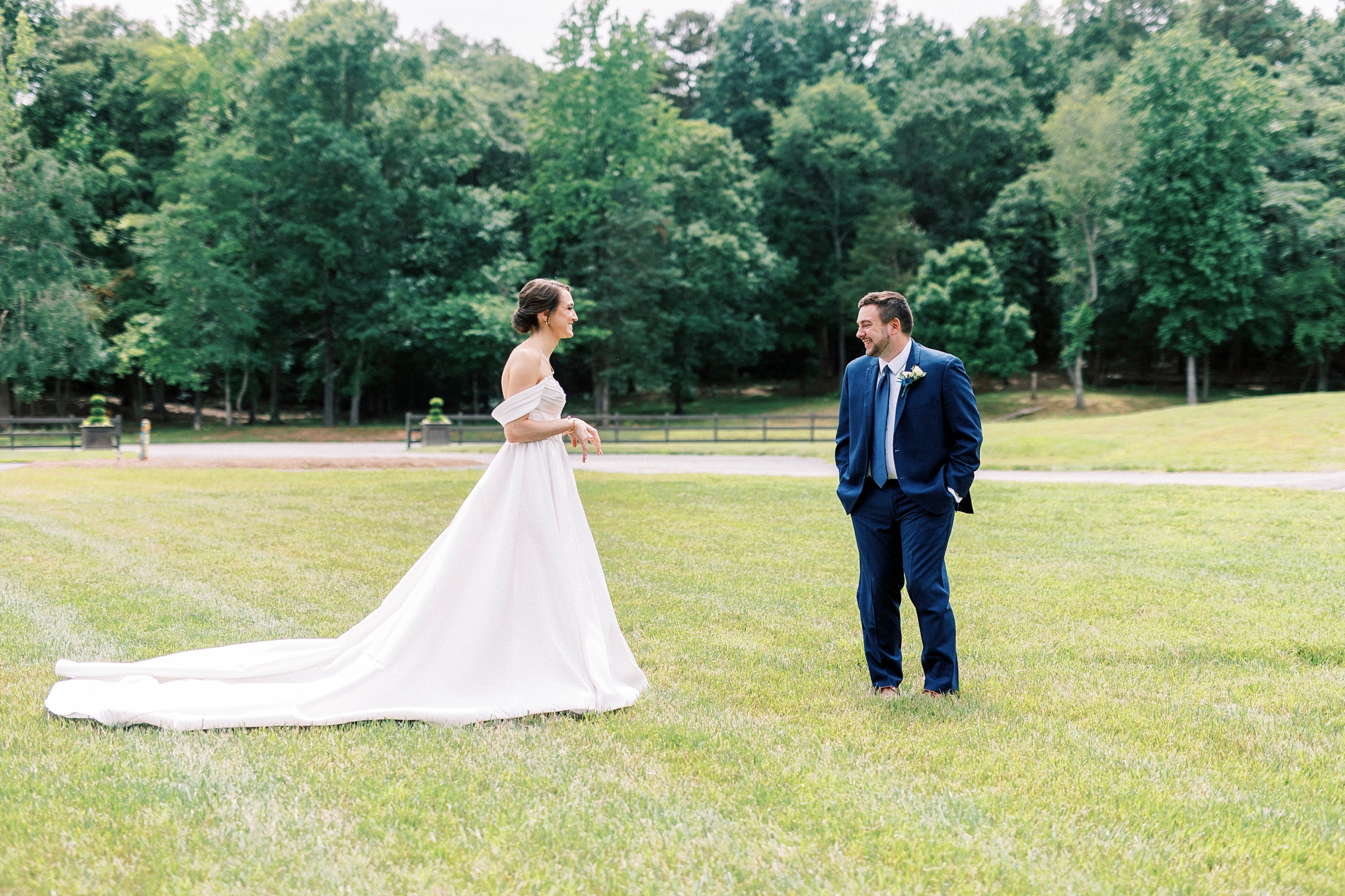 groom in navy suit turns to look at bride during first look at Low Meadows Estate