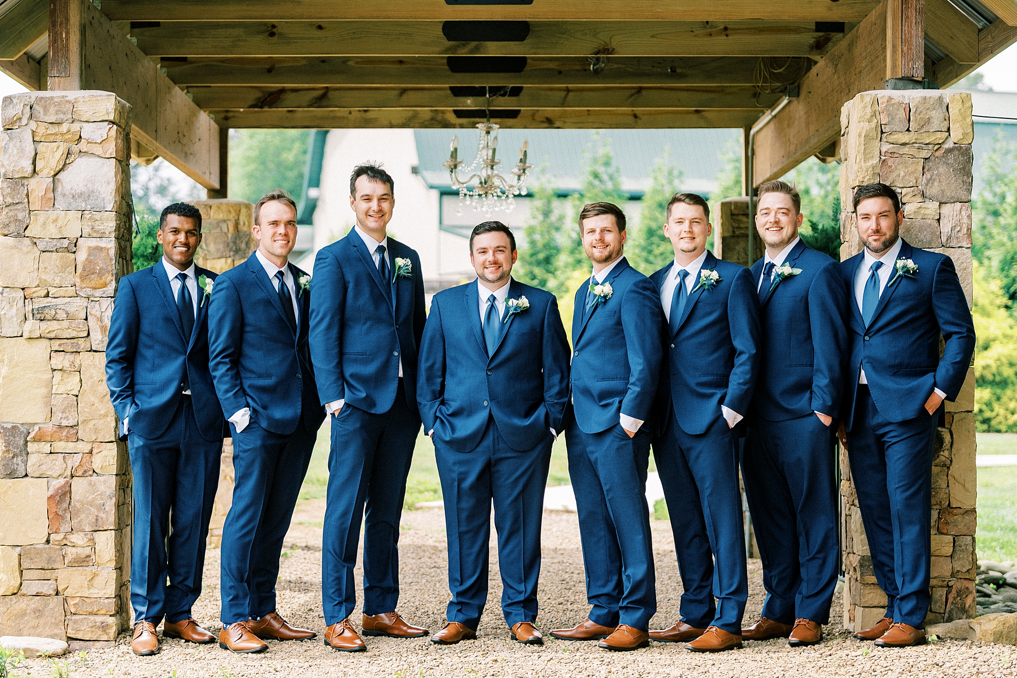 groom stands in a line with groomsmen in navy blue suits