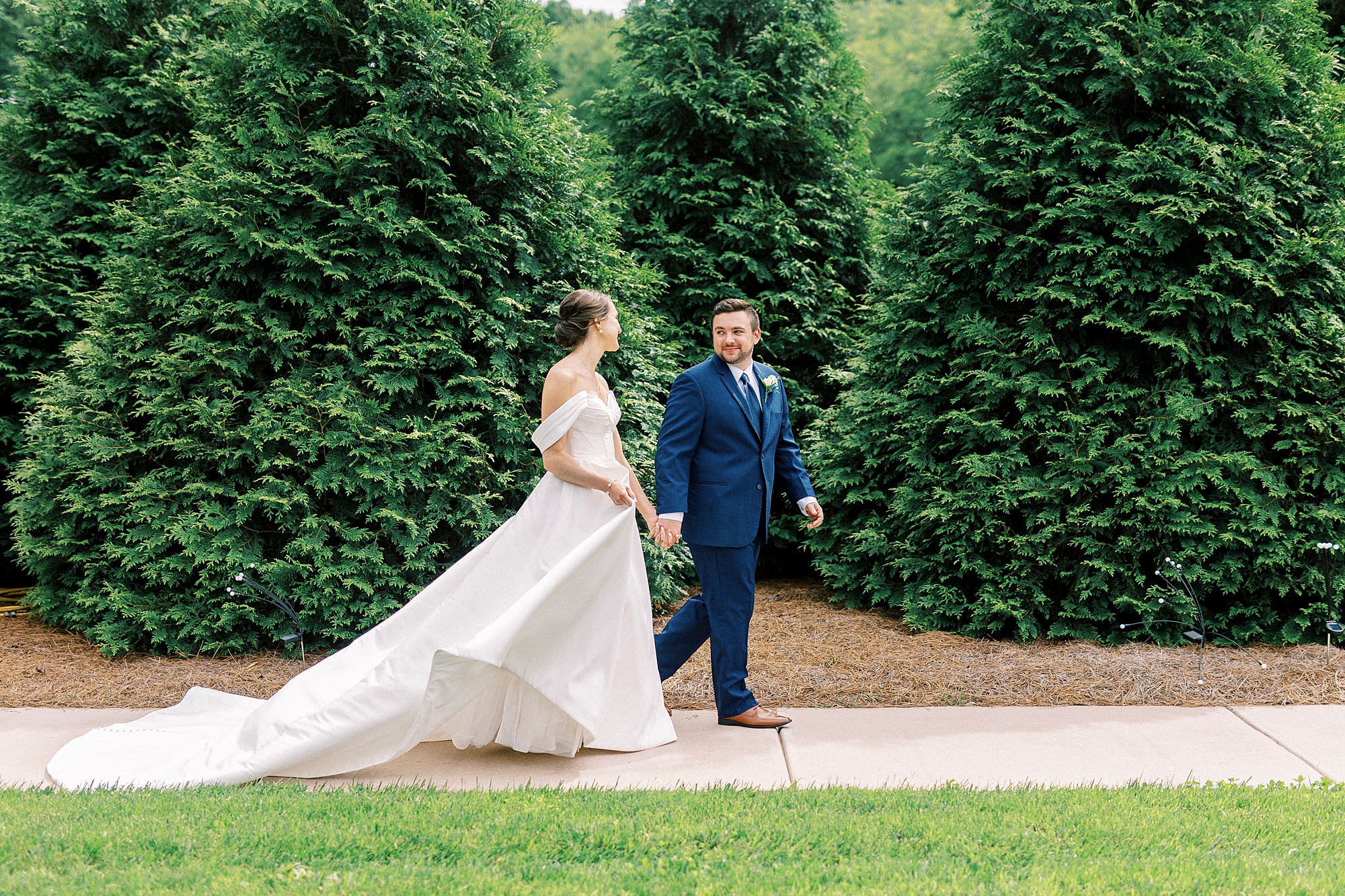 groom leads bride through gardens of Low Meadows Estate
