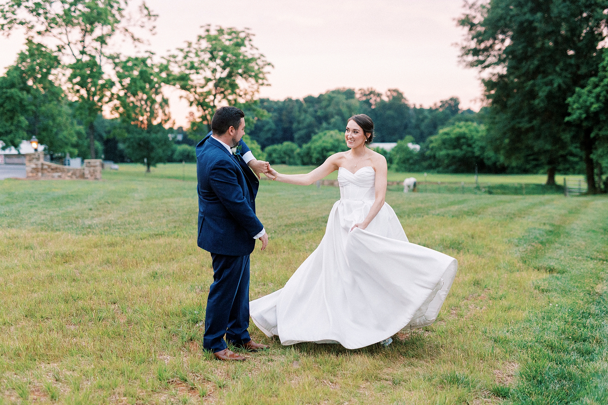 groom twirls bride out away from him on lawn at Low Meadows Estate