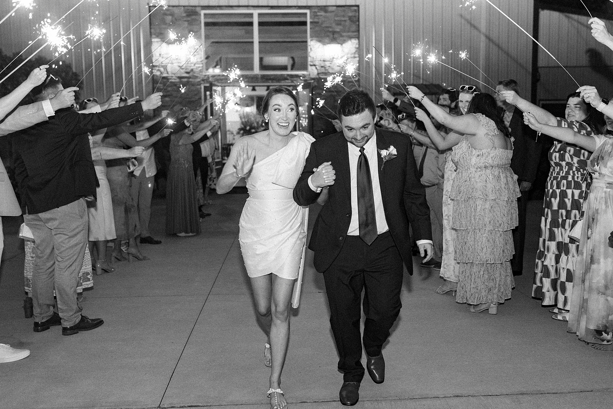 groom leads bride through sparkler exit outside Low Meadows Estate