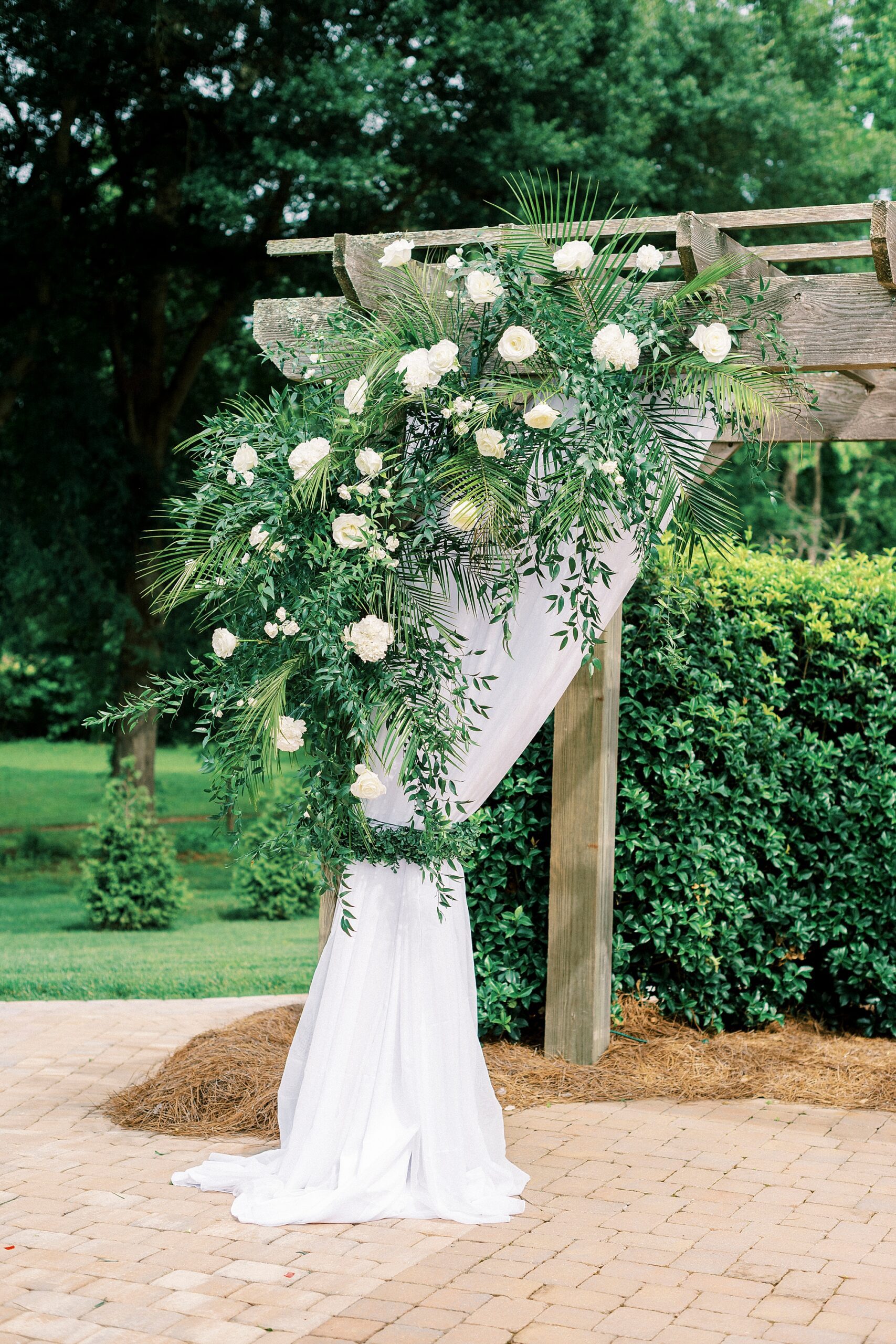 wedding ceremony floral spray with white flowers on wooden arbor 