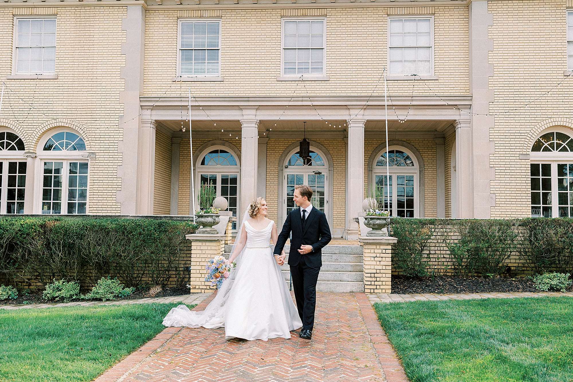 bride and groom hold hands walking on brick pathway at Separk Mansion