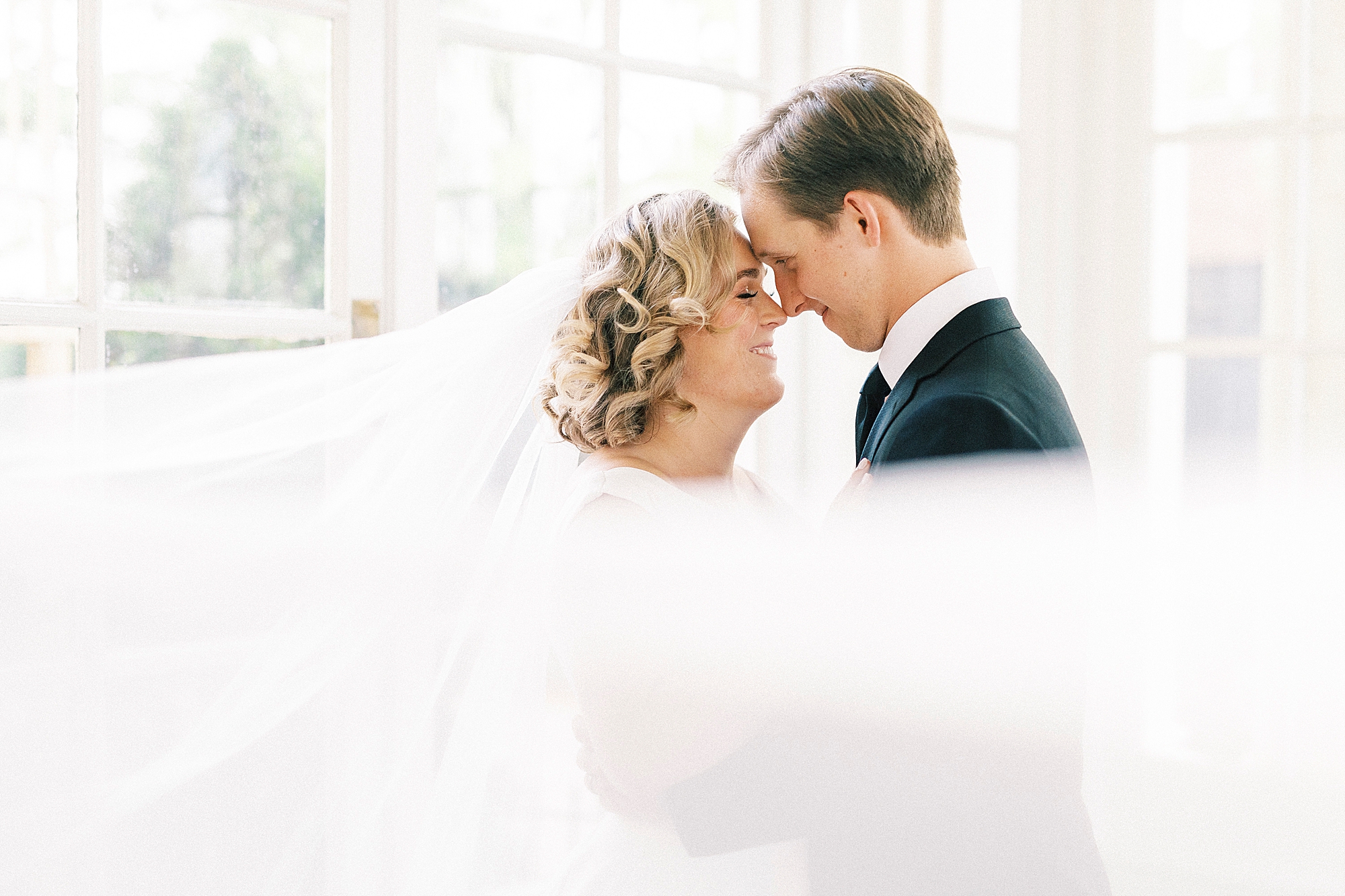 bride and groom stand in sunroom of Separk Mansion
