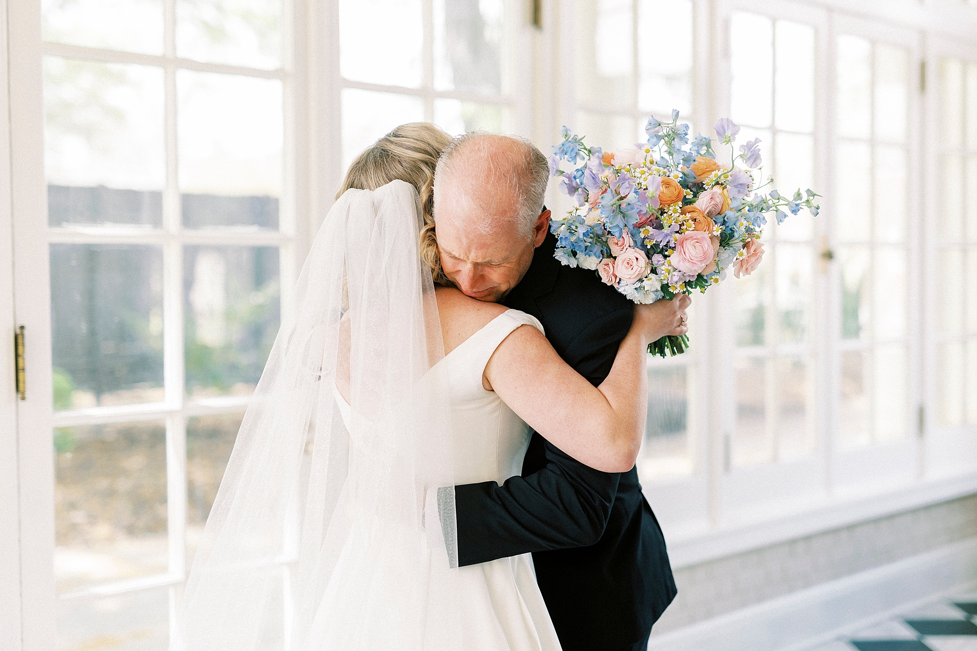father of the bride hugs her tight during first look in sunroom