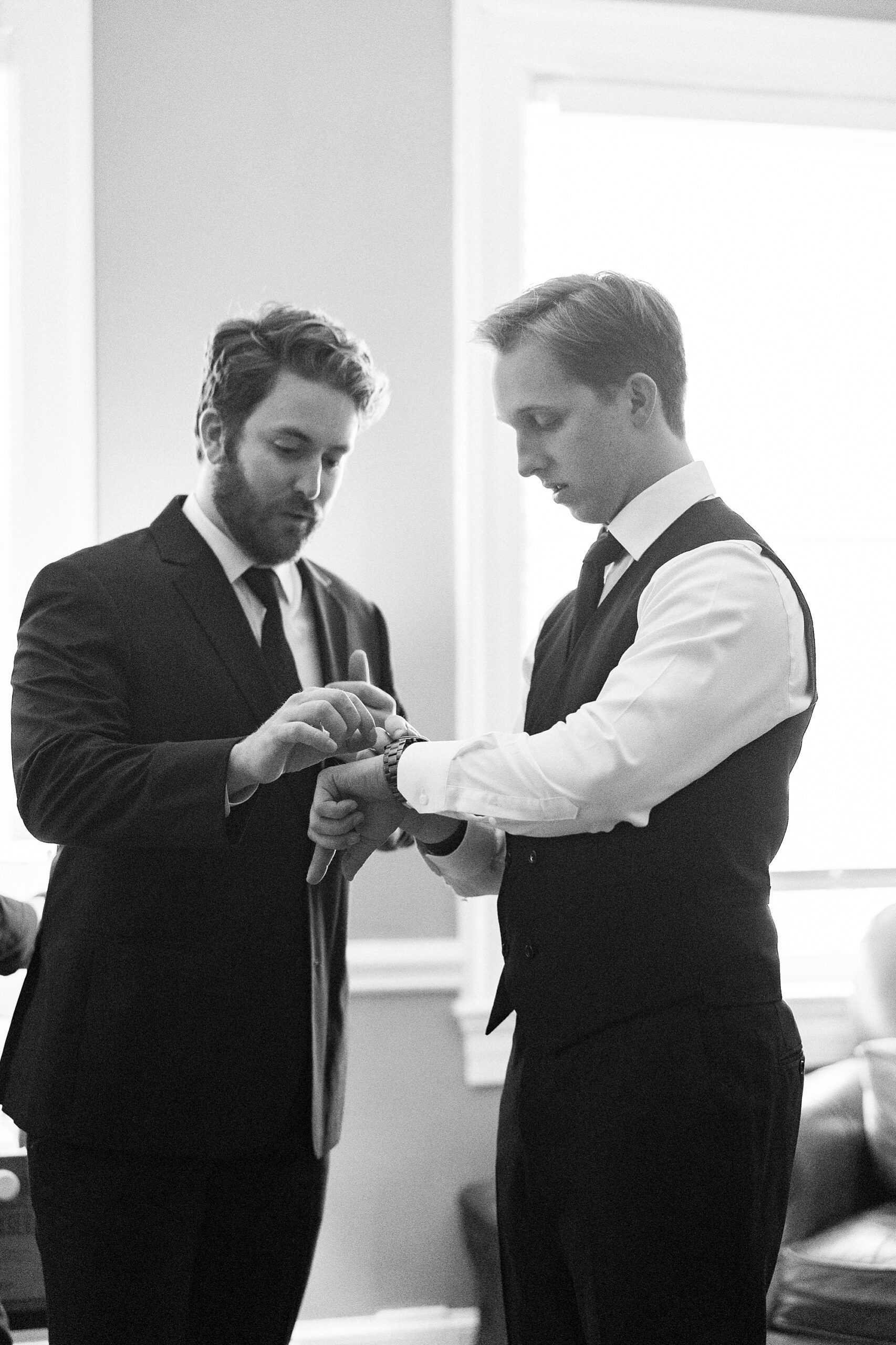 groomsman helps groom with cufflinks 