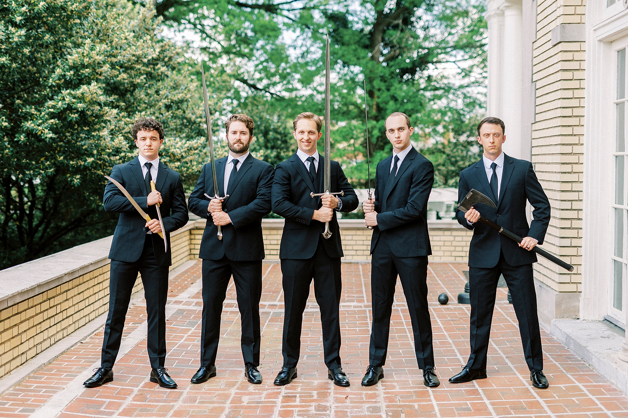 groom and groomsmen pose with swords outside Separk Mansion