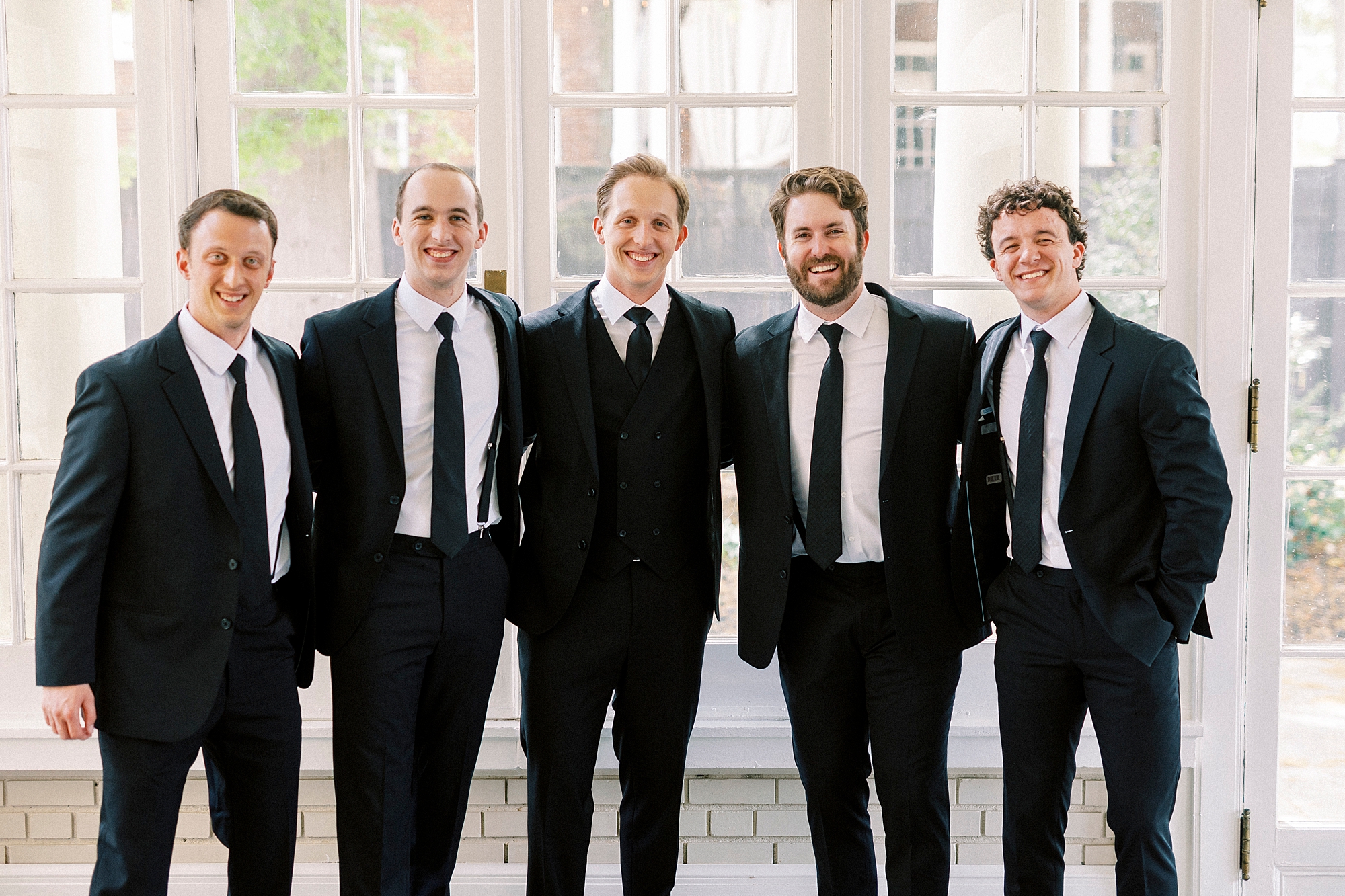 groom hugs groomsmen in line during portraits at Separk Mansion
