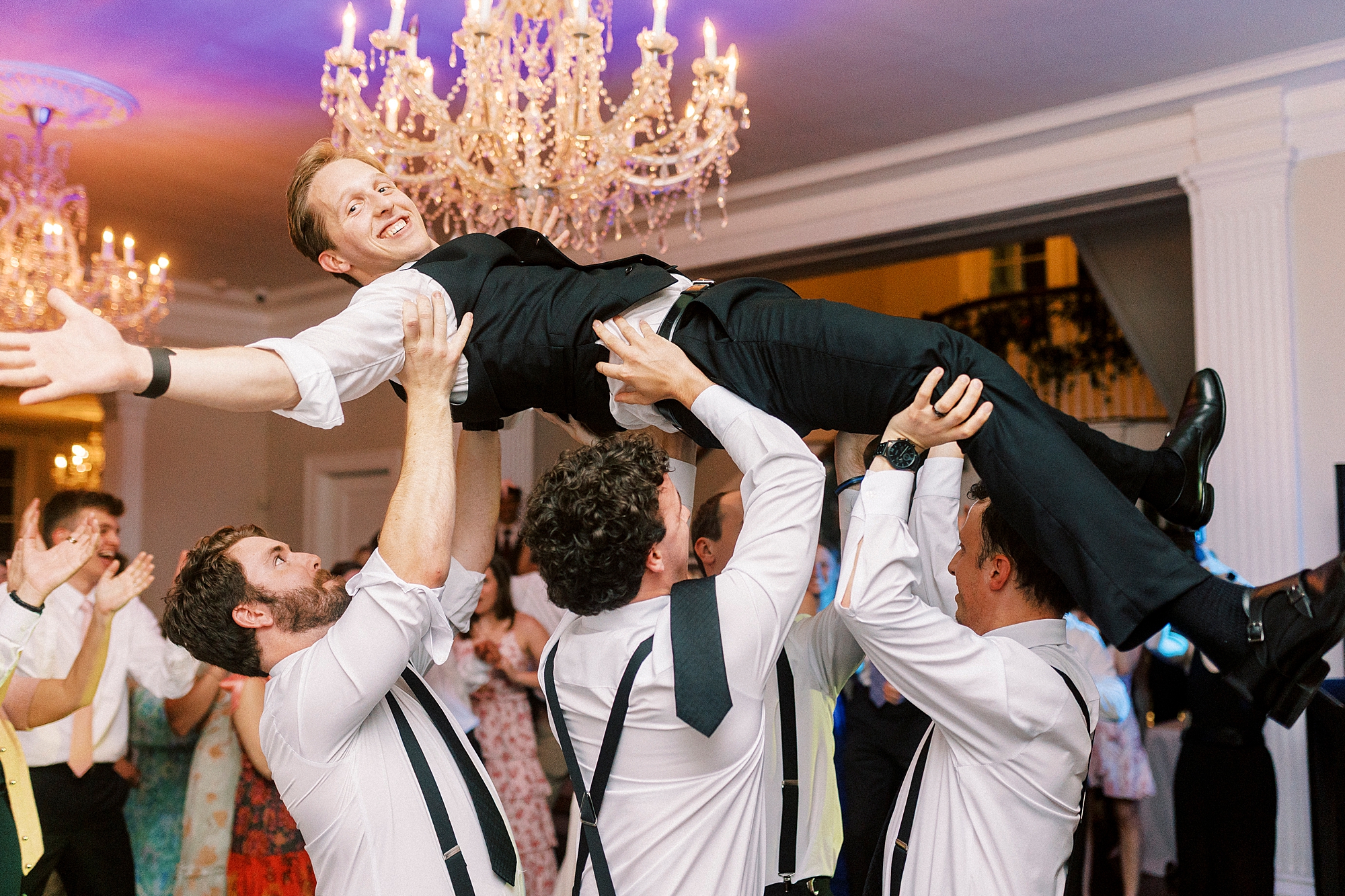 groomsmen lift up groom during dances at reception 