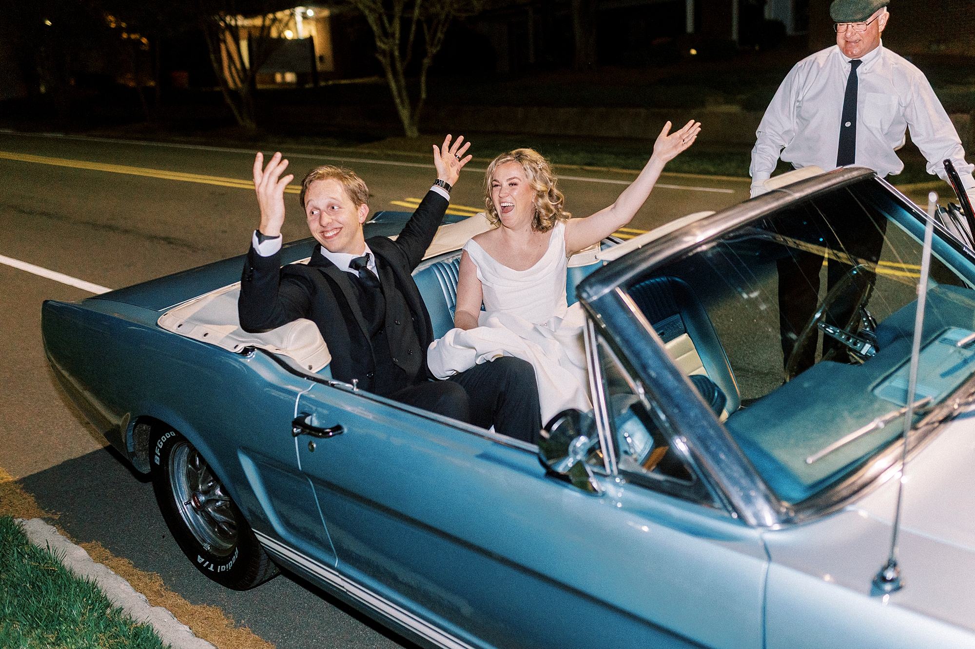 newlyweds wave in classic blue convertible leaving reception 