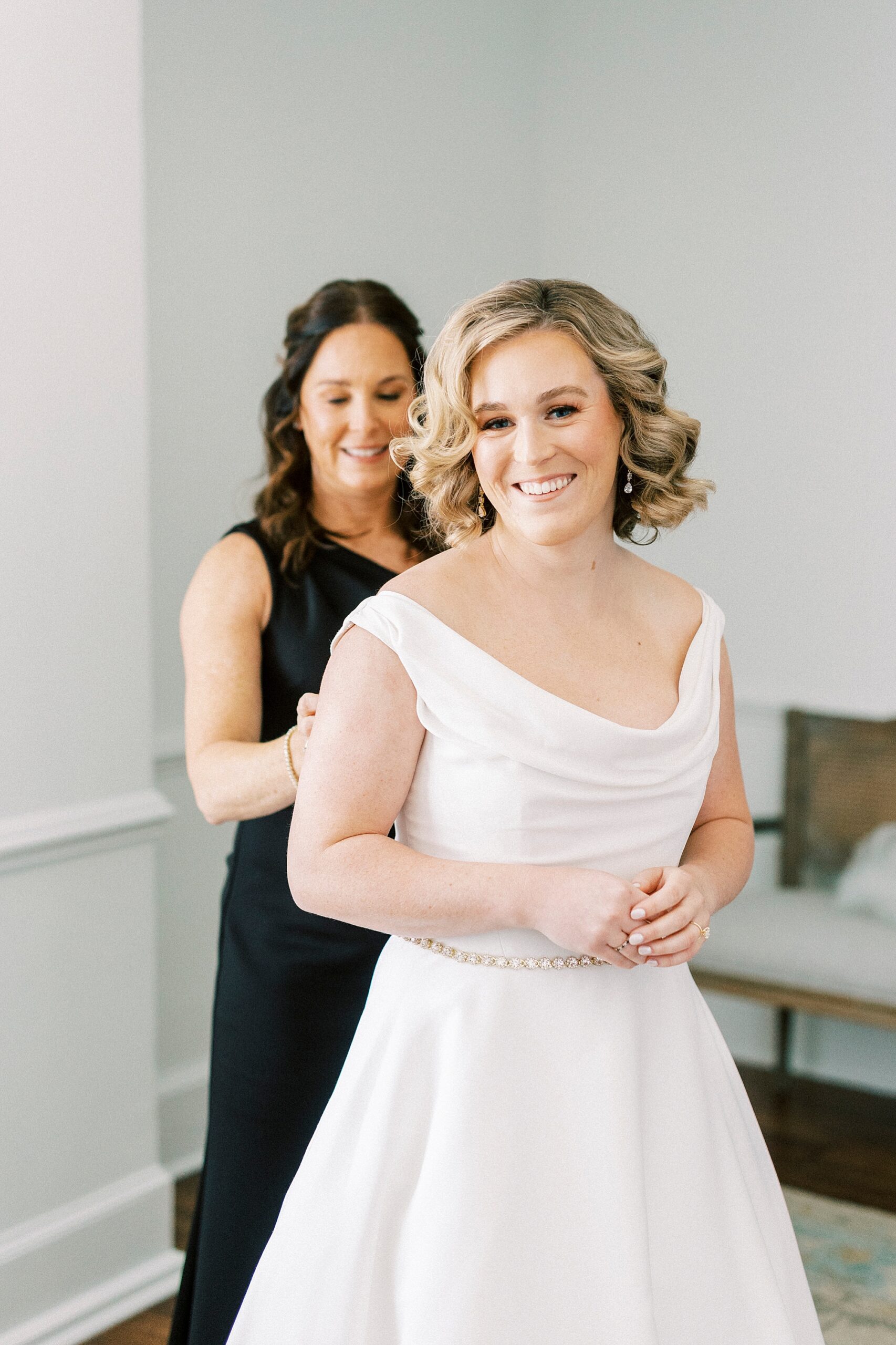bridesmaid helps bride into wedding gown in bridal suite at Separk Mansion