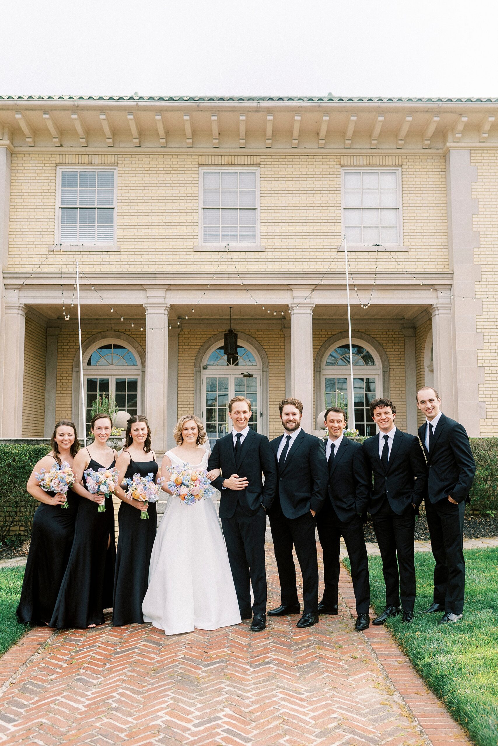 bride and groom stand with wedding party in front of Separk Mansion