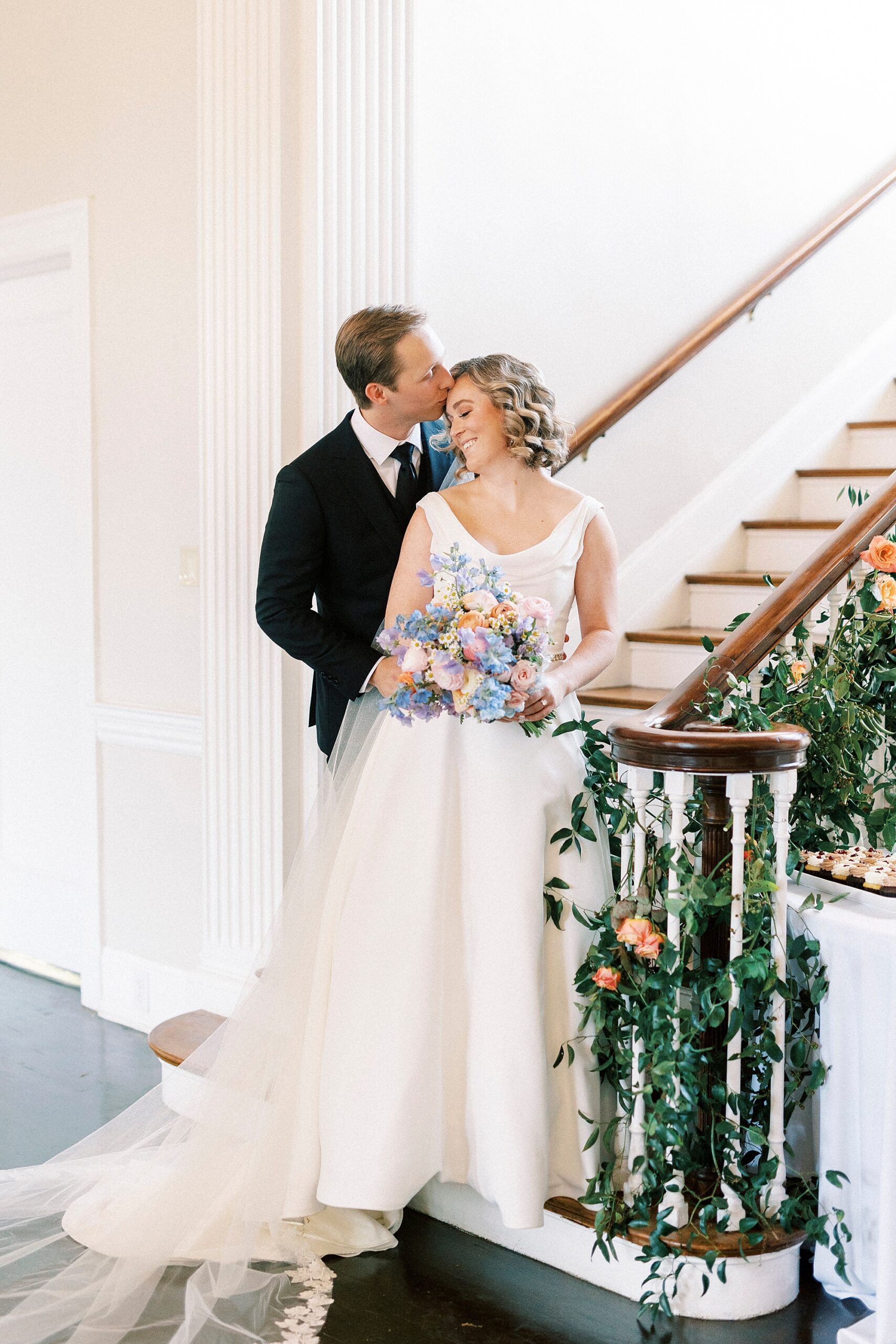 groom kisses bride's forehead standing on staircase inside Separk Mansion