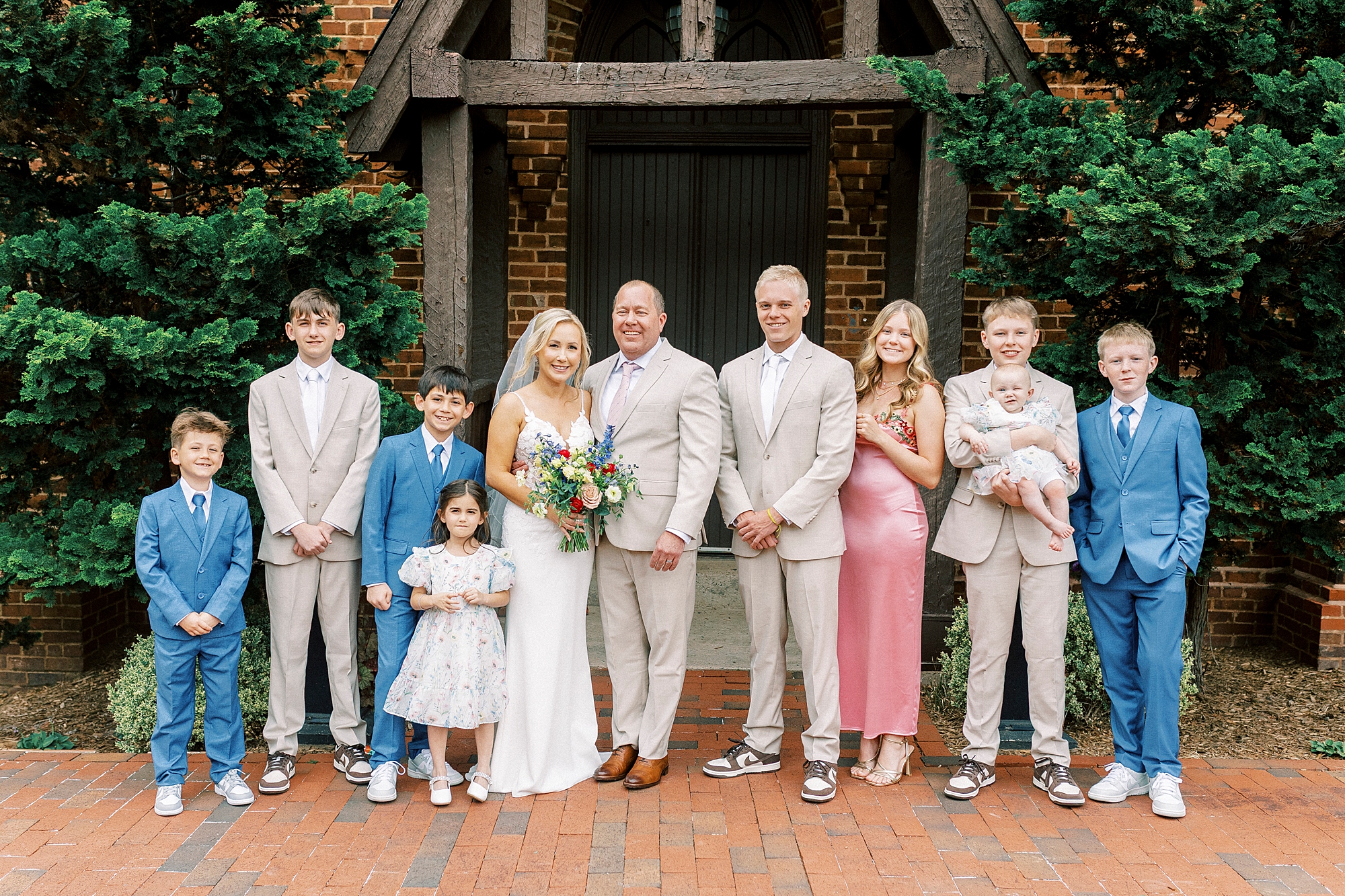 bride and groom pose with 9 children outside St. Mary's Chapel