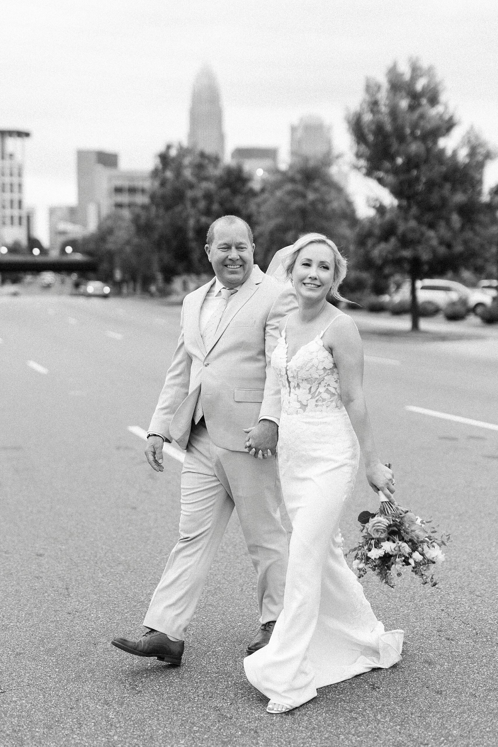 bride and groom hold hands crossing road in Uptown Charlotte