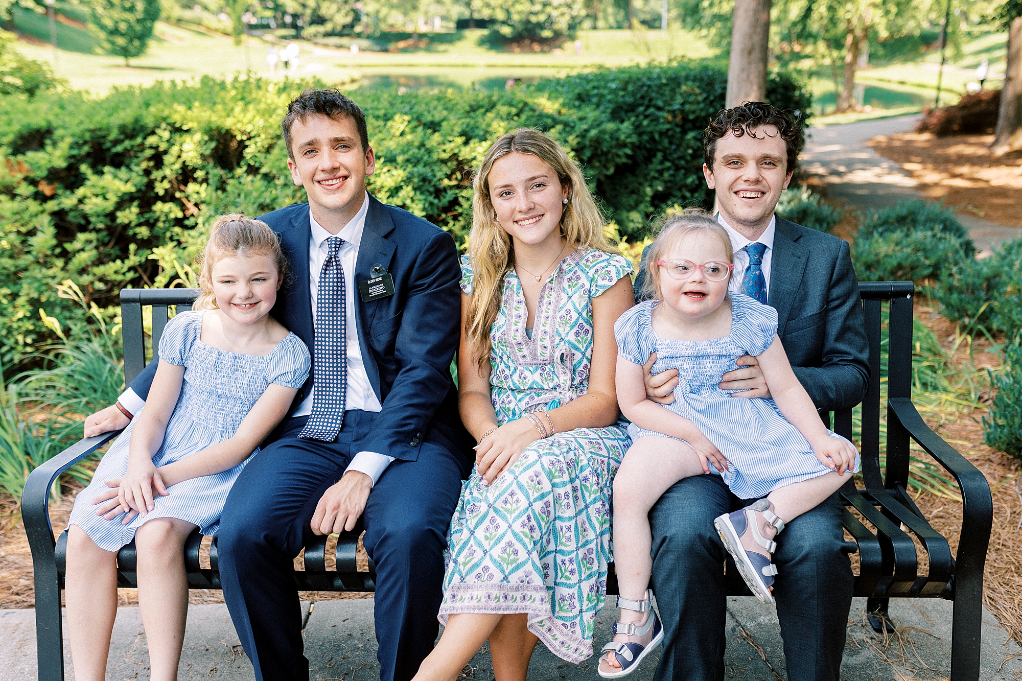 five siblings sit on park bench during summer family photos in Cullman Park