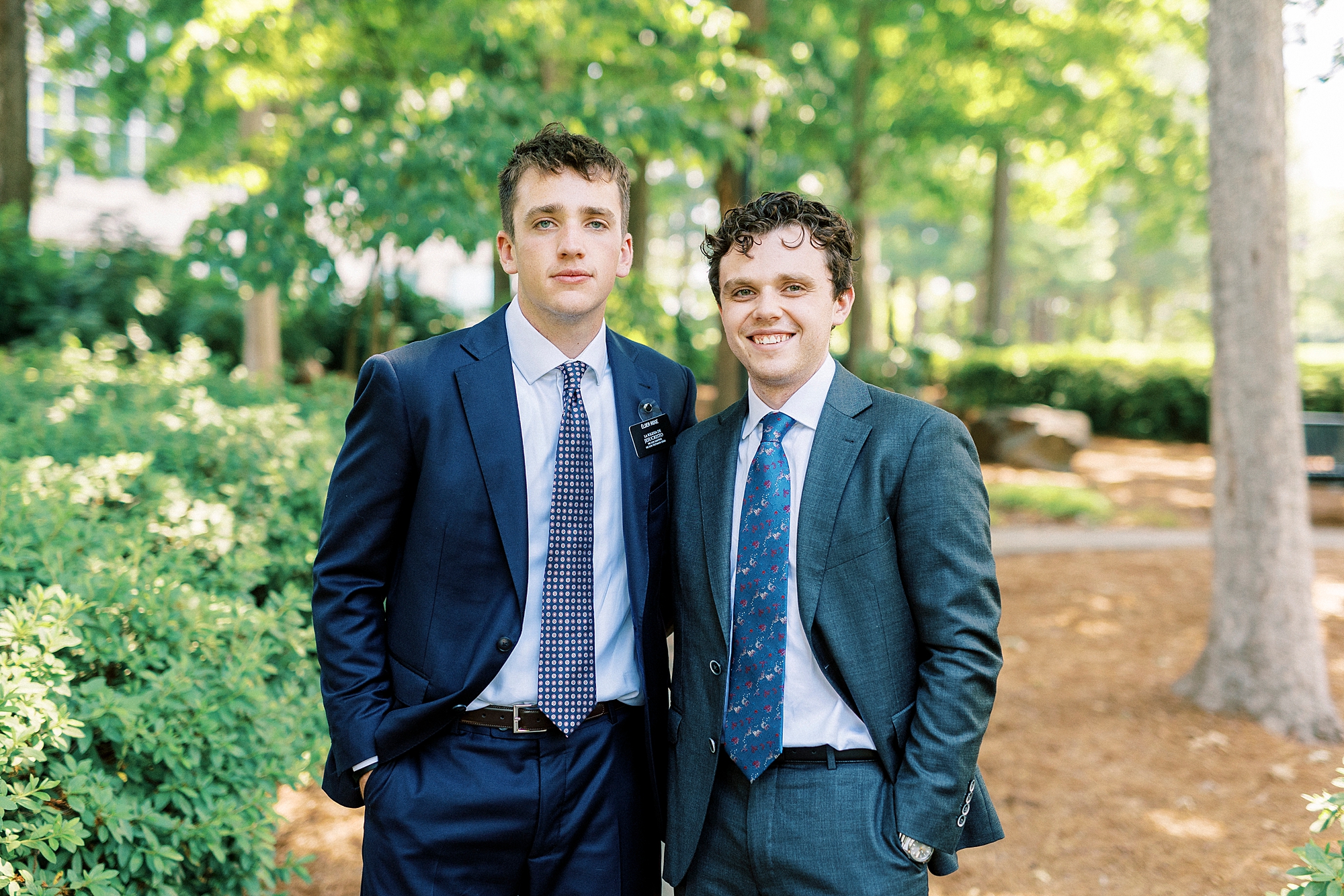 teenage brothers stand together in suits on path at Cullman Park