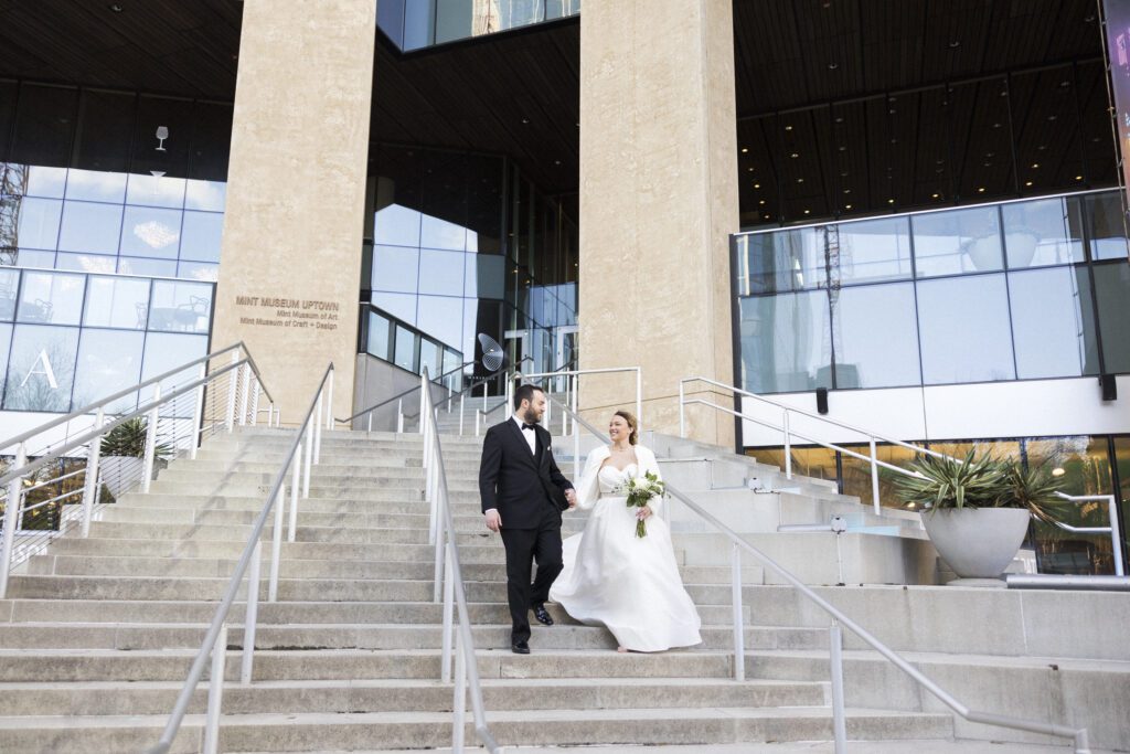 bride and groom walking down stairs of mint museum in uptown Charlotte 