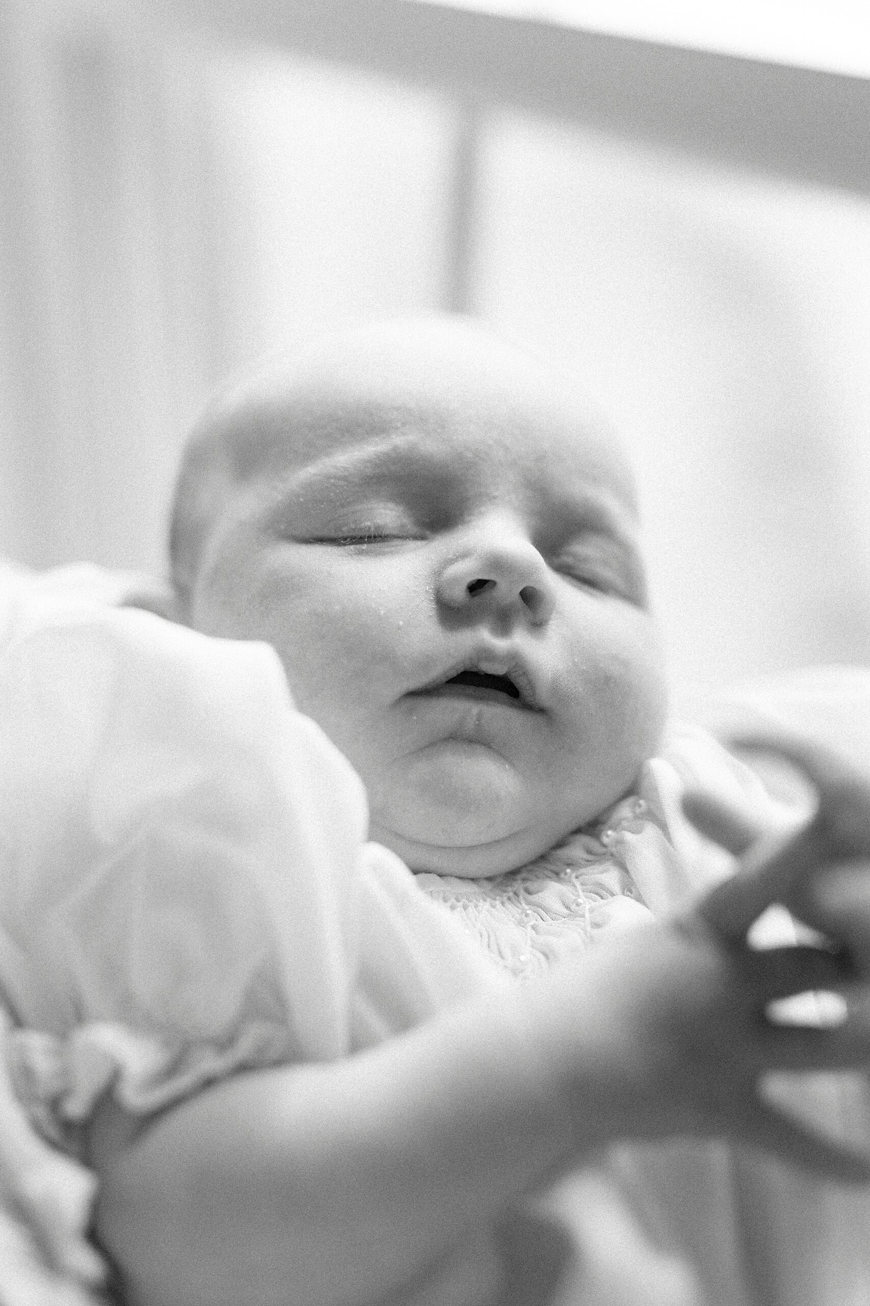 baby sleeps in black and white photo by window