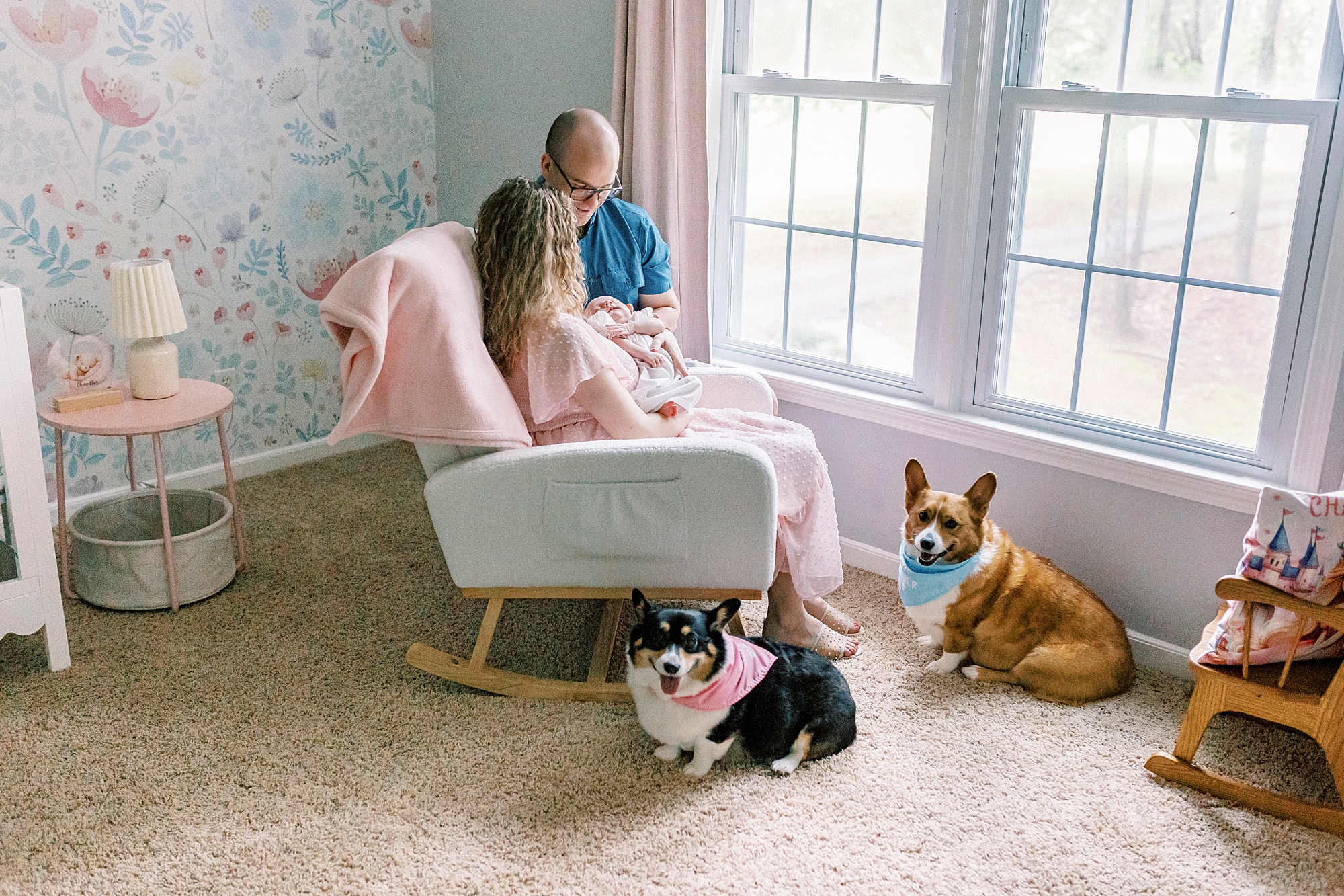 parents sit with newborn daughter and puppies at feet