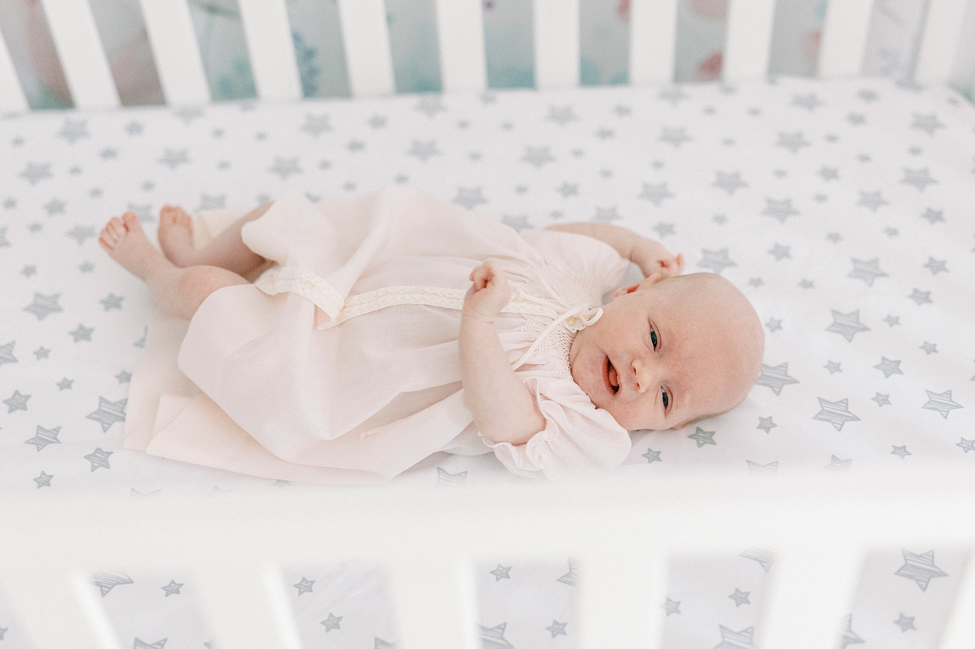 baby girl sleeps in white wooden crib