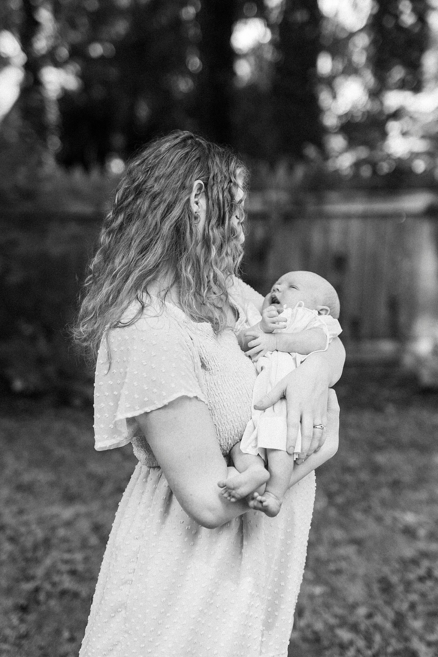 mother holds daughter in her arms during lifestyle newborn session in Winston-Salem