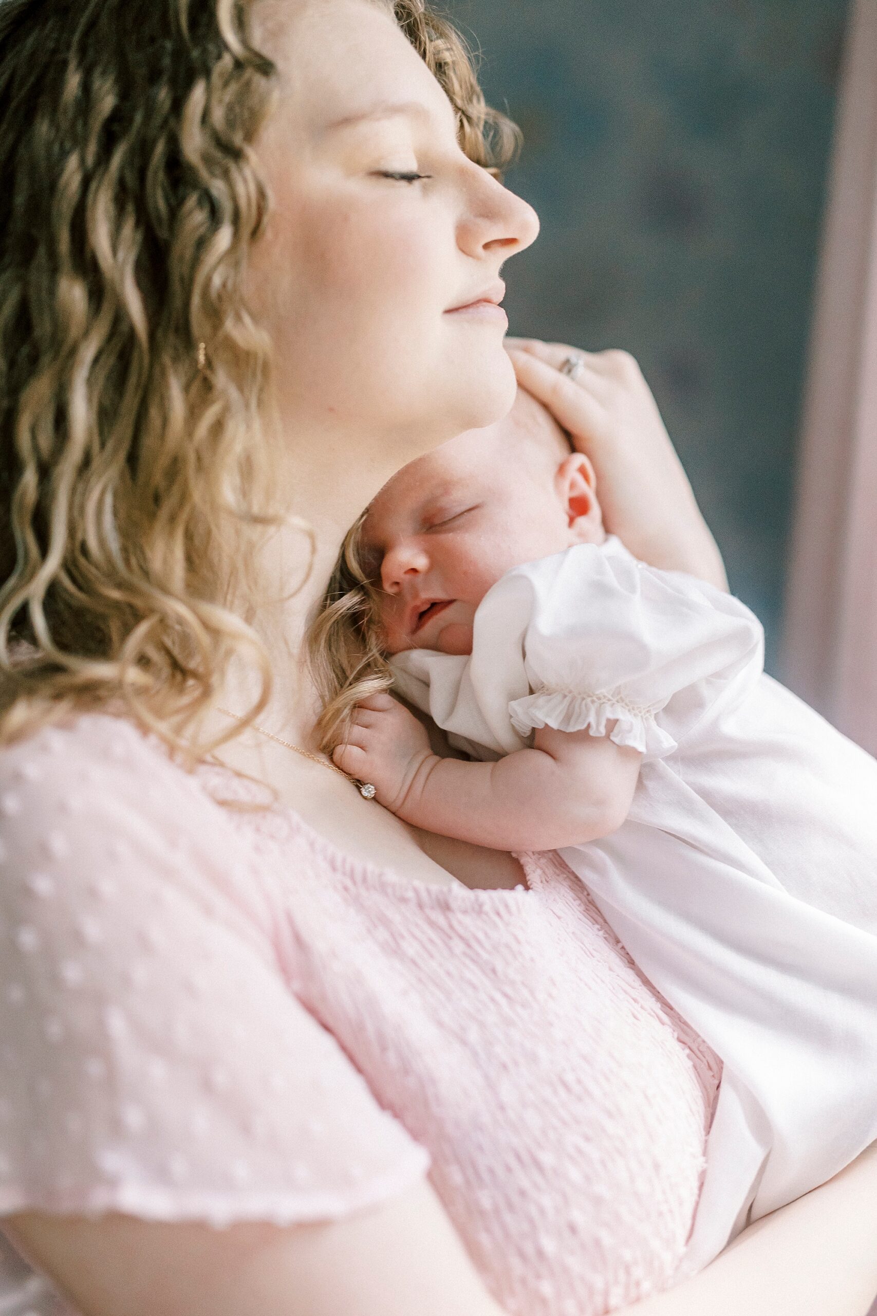 mom holds baby girl on her chest during lifestyle newborn session with Winston-Salem family photographer