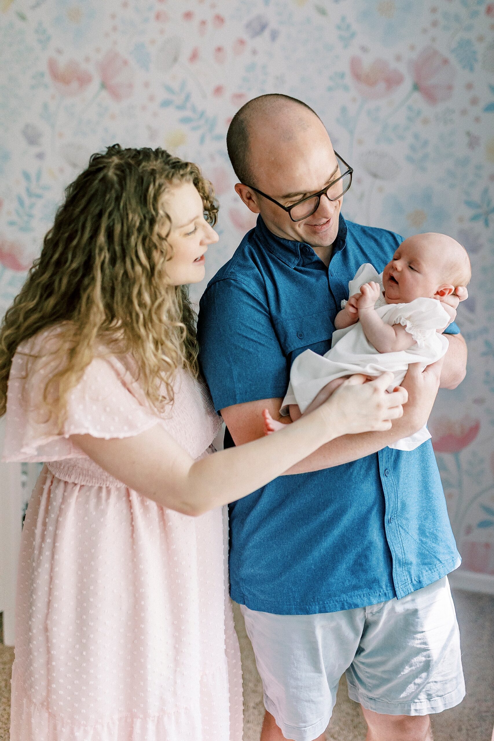 new parents smile at baby girl during lifestyle newborn session with Winston-Salem family photographer