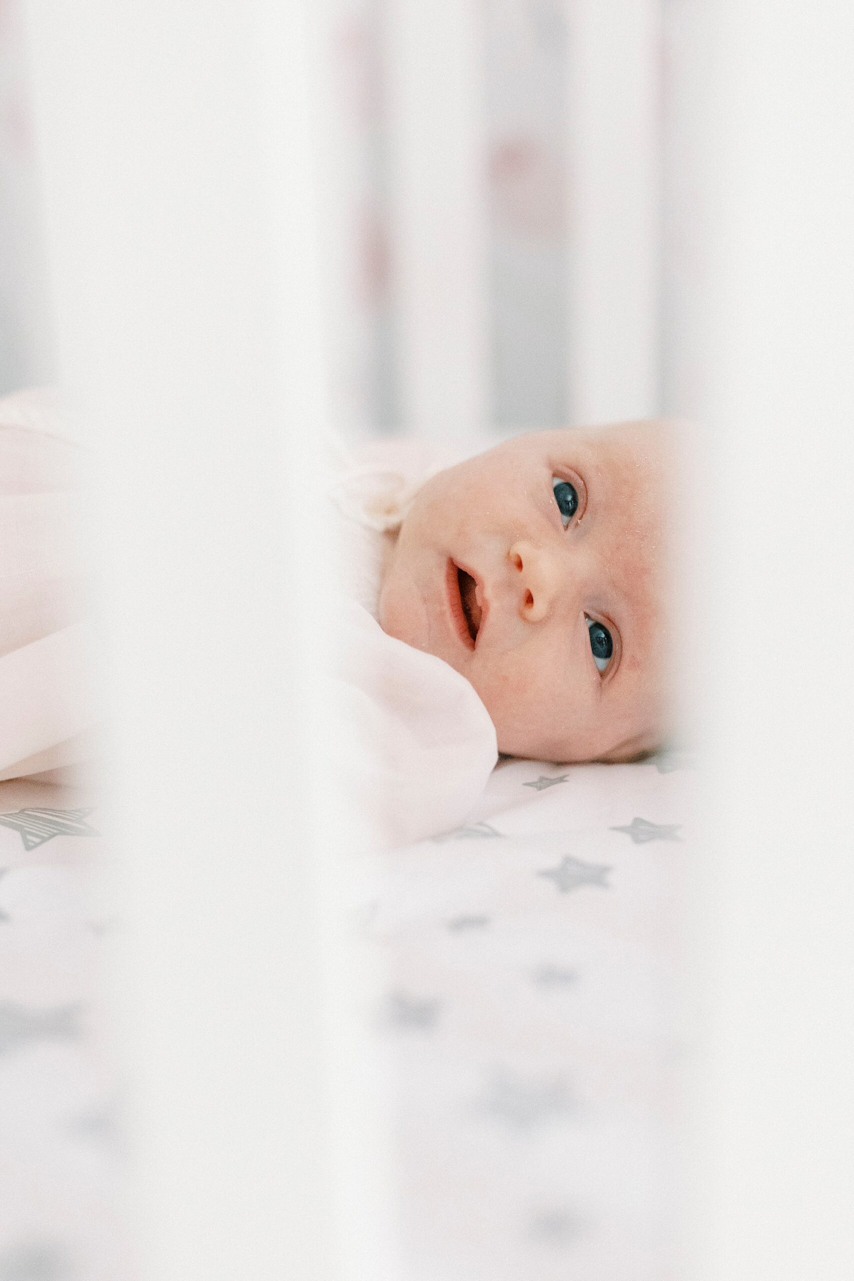 baby looks through wrungs of crib 