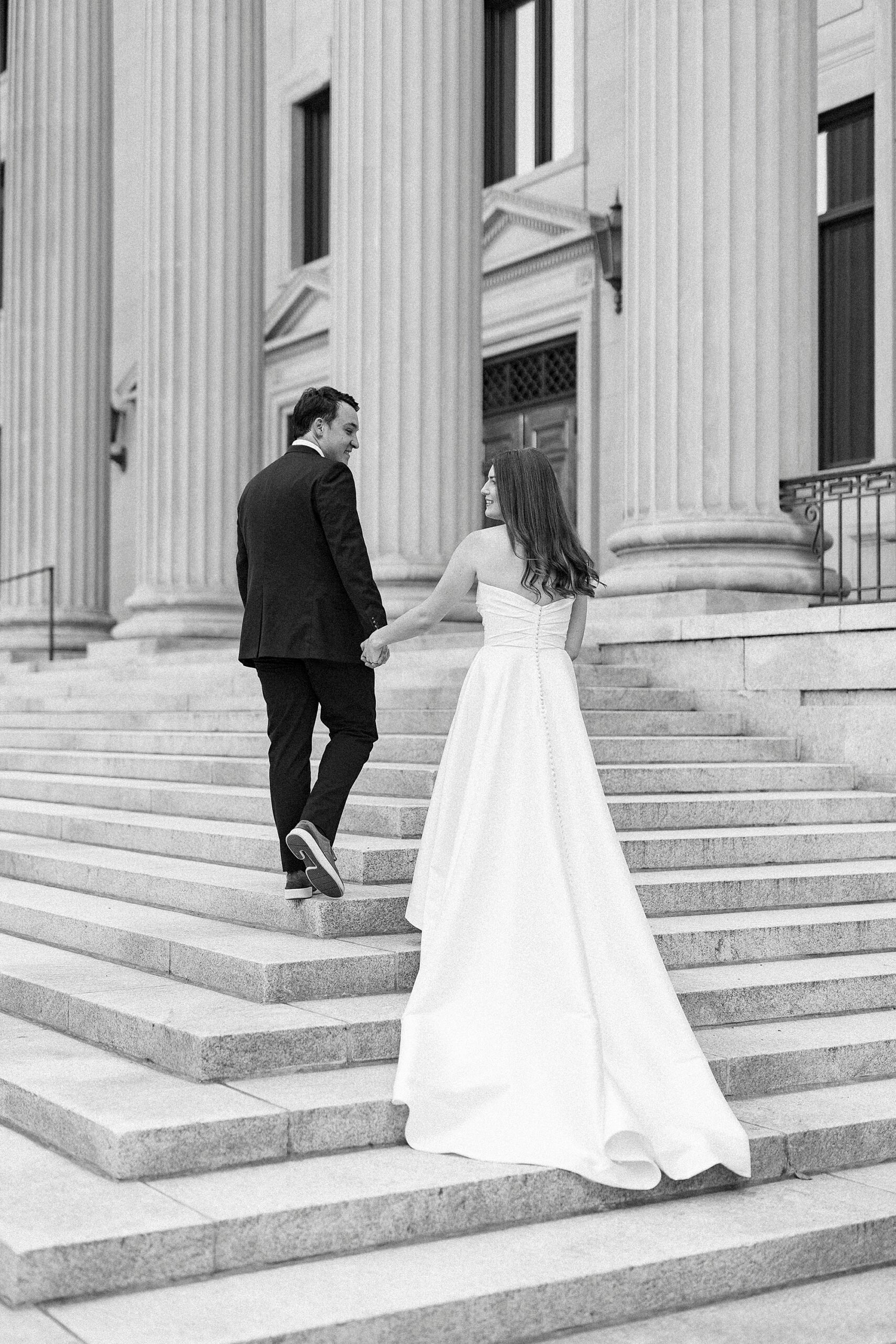groom leads bride up stairs in uptown Charlotte 
