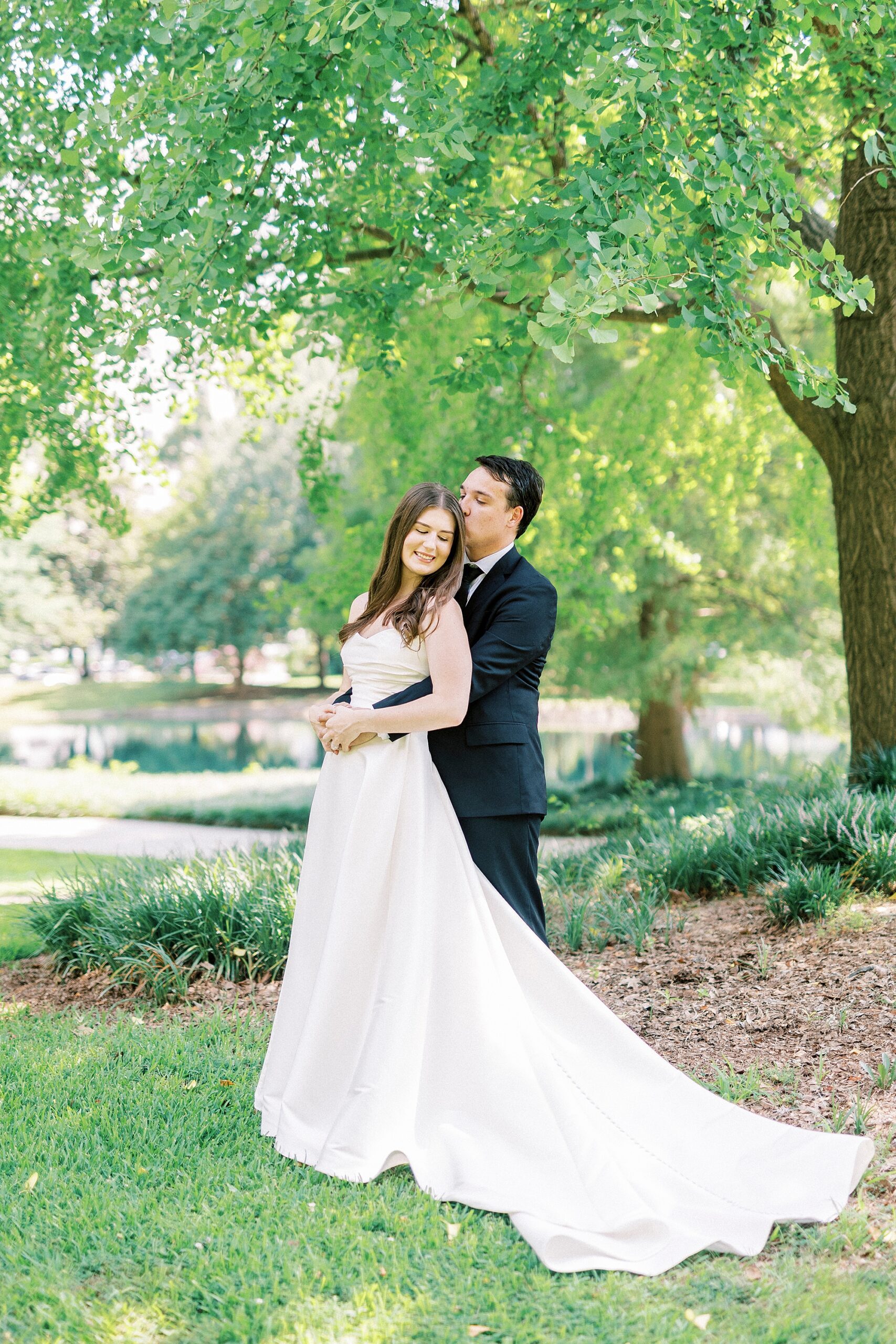groom hugs bride from behind during wedding photos in Uptown Charlotte 