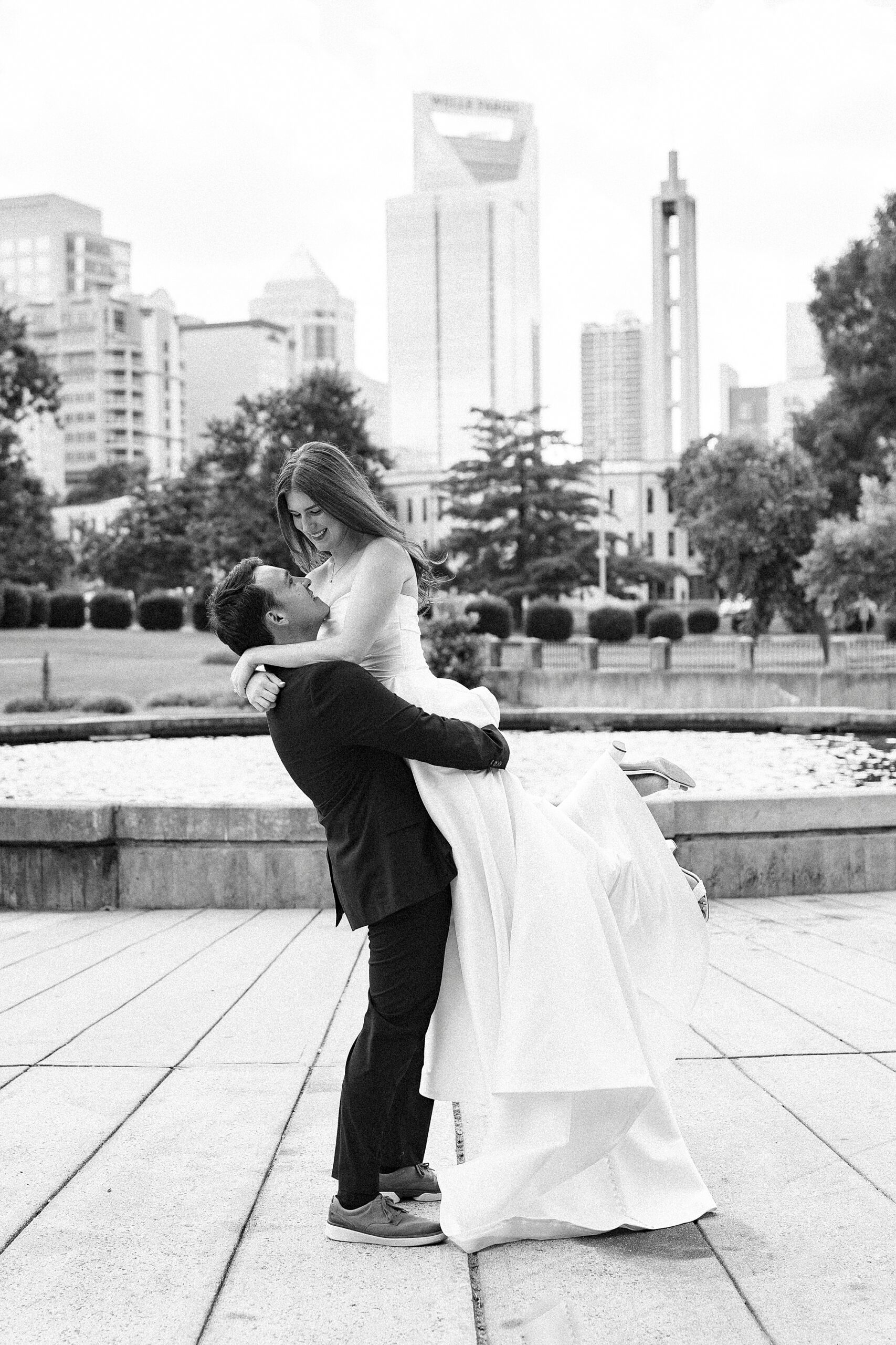 groom lifts up bride during photos in park in Charlotte NC