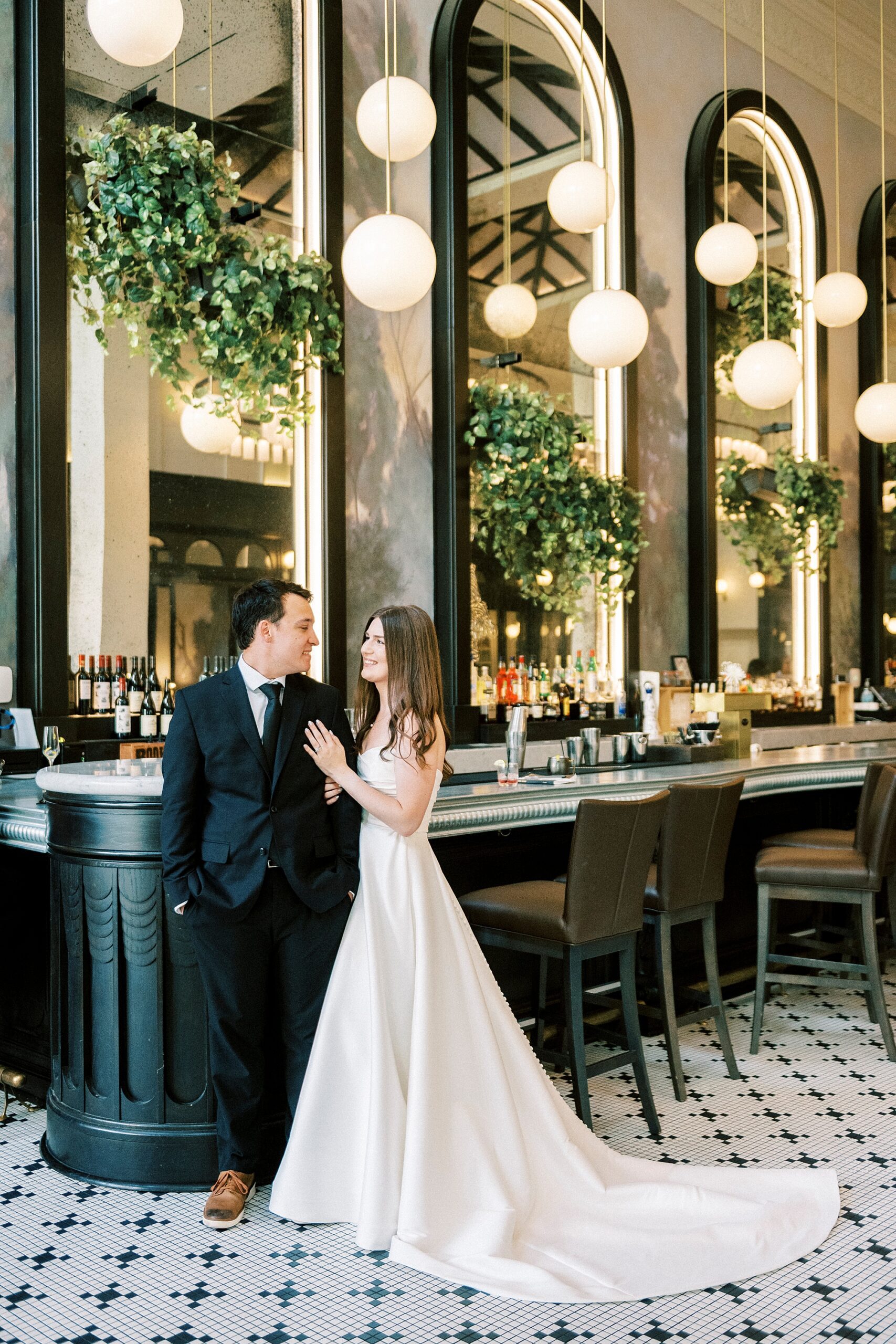 bride and groom lean against bar inside French restaurant 
