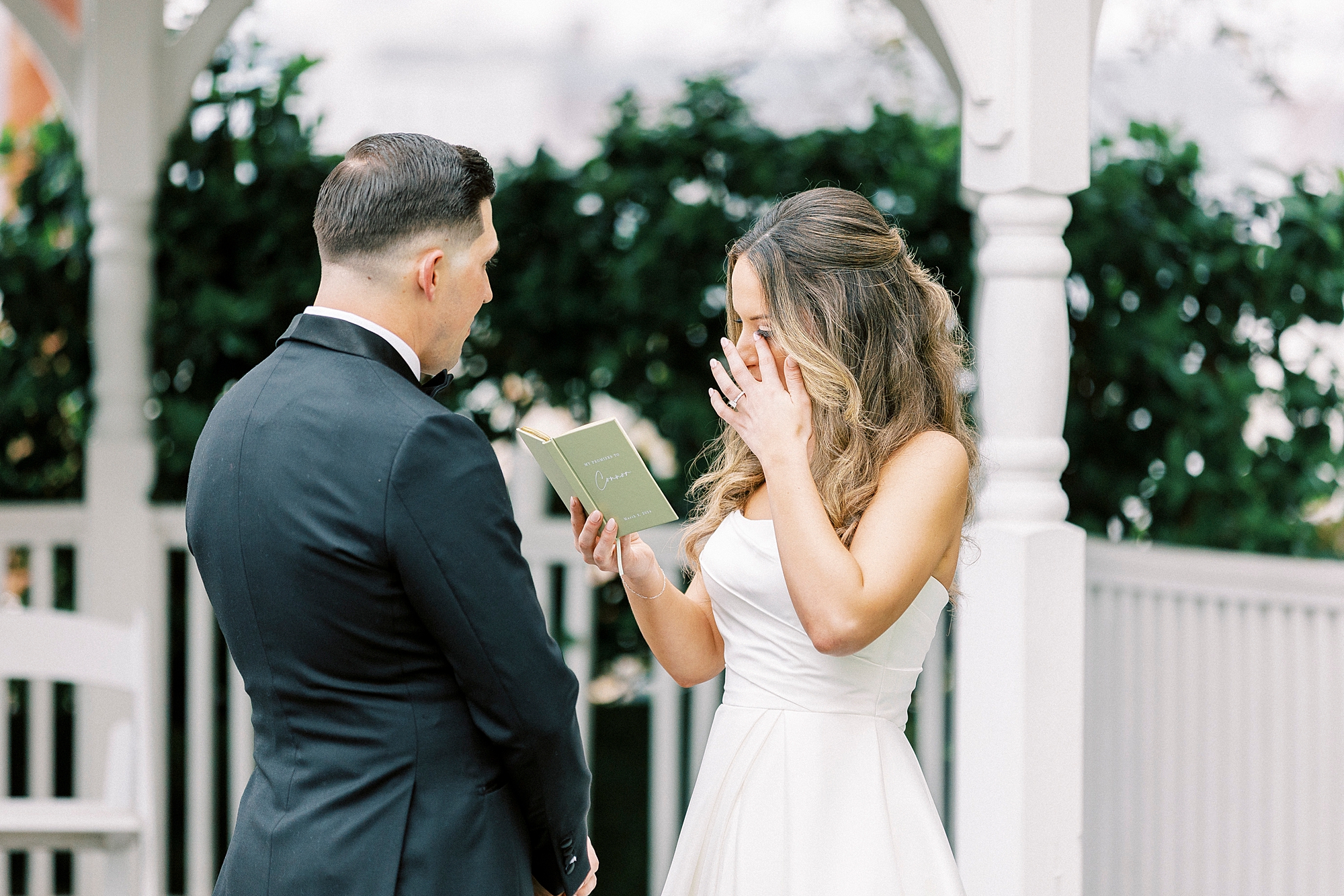 bride wipes away tears as she reads vows to groom