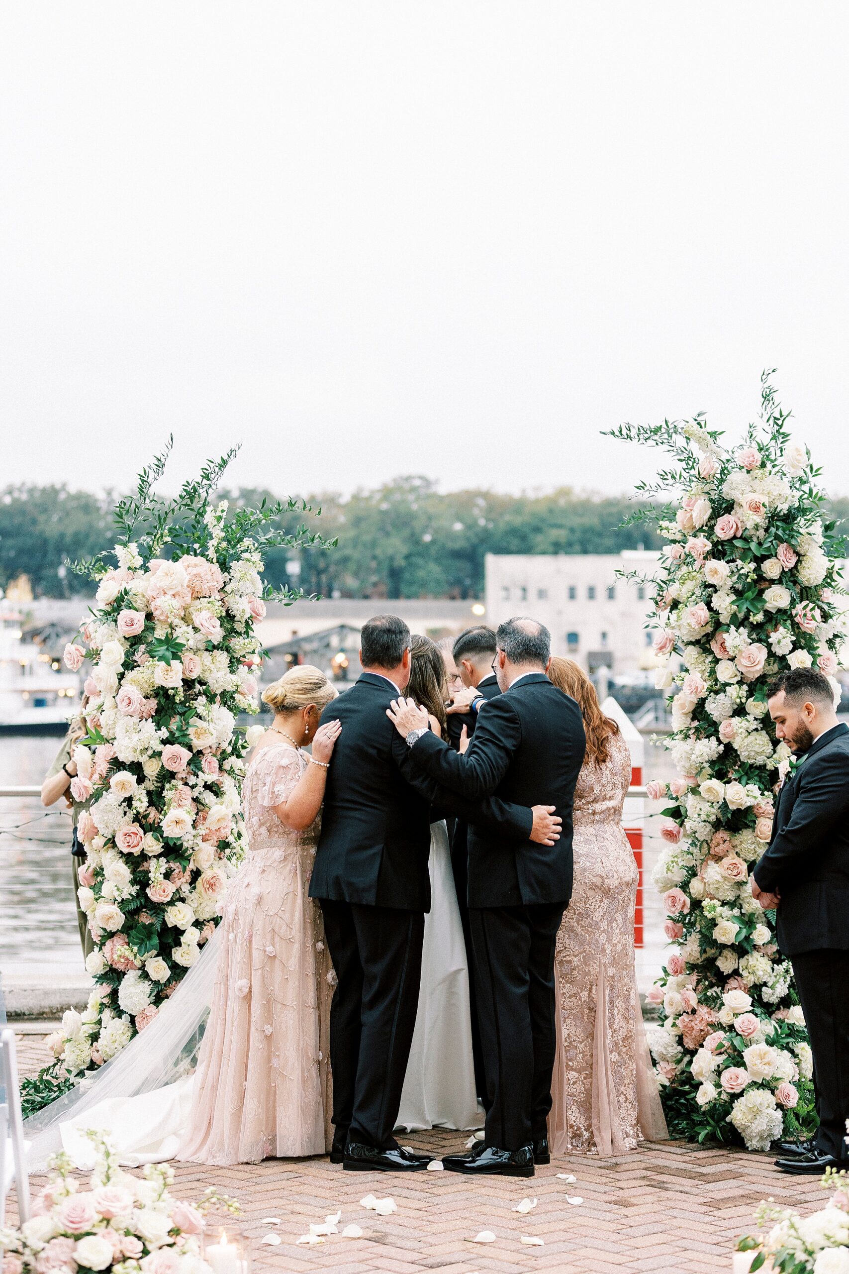 family surrounds bride and groom in prayer 