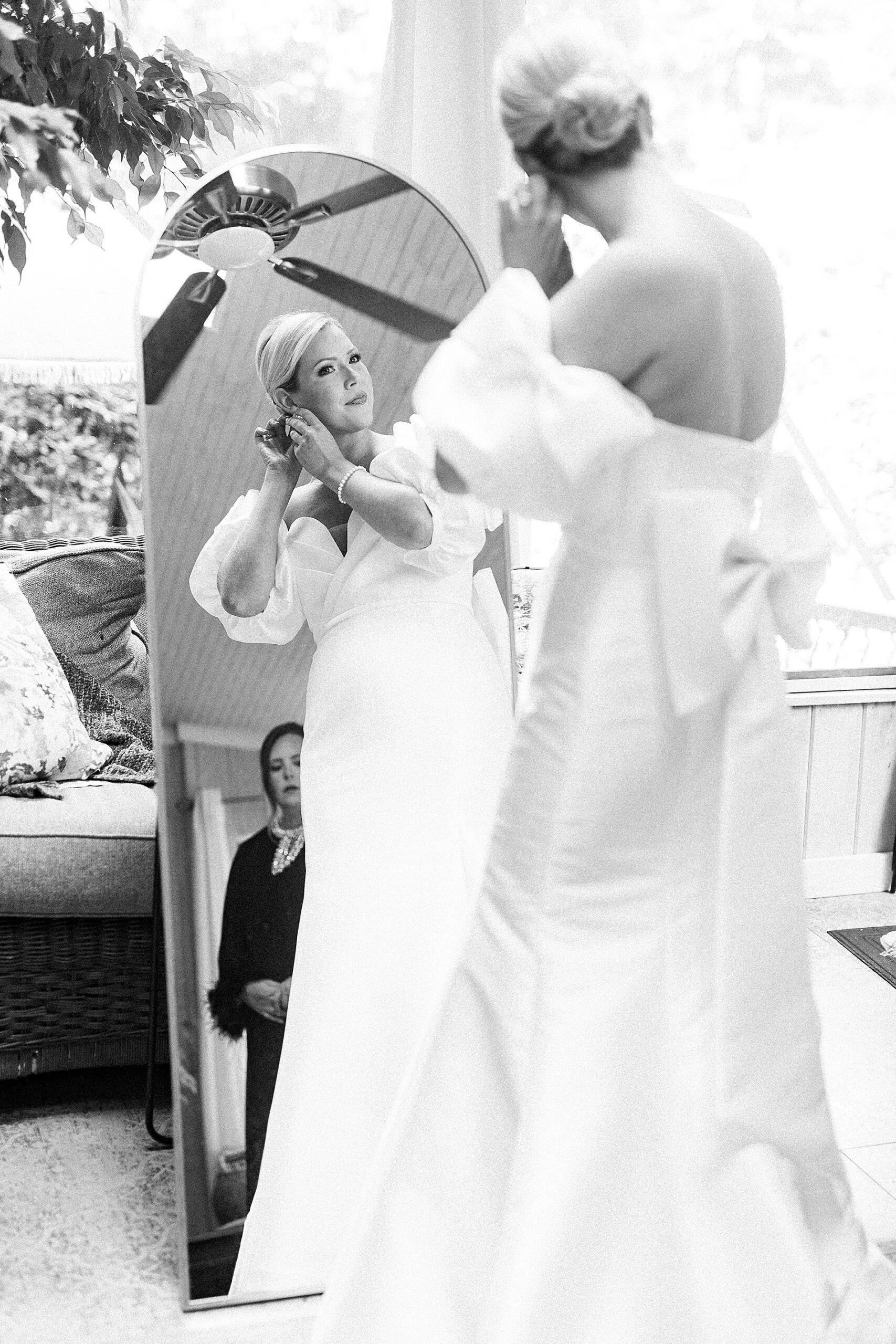 bride putting earrings in while looking the mirror