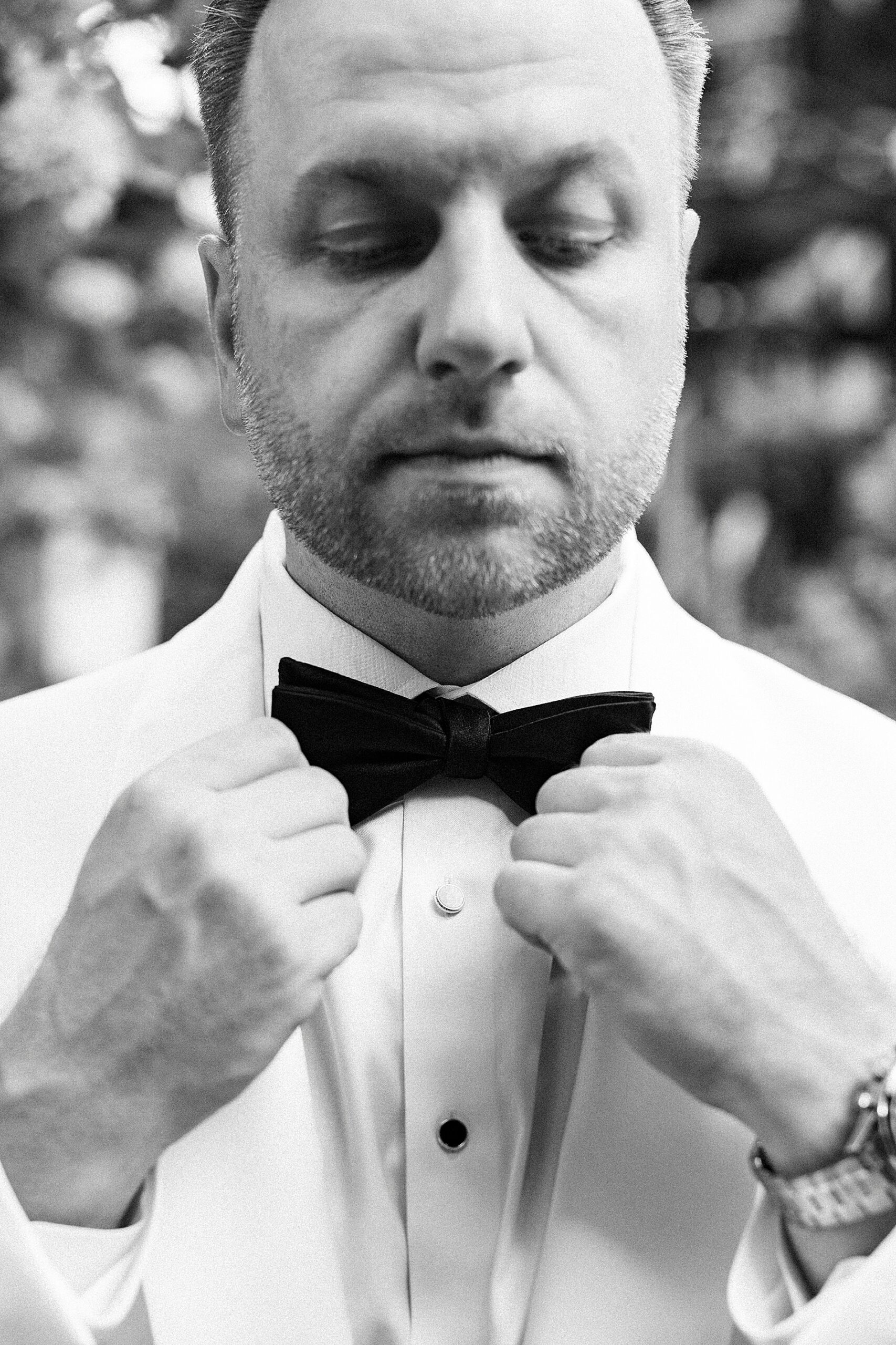 groom puts on black bowtie