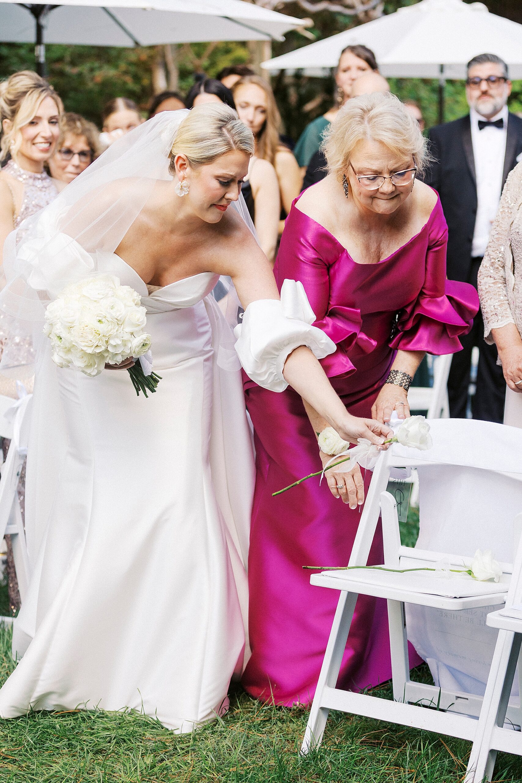 bride and mom lay white flower on chair in remembrance of loved one at wedding ceremony