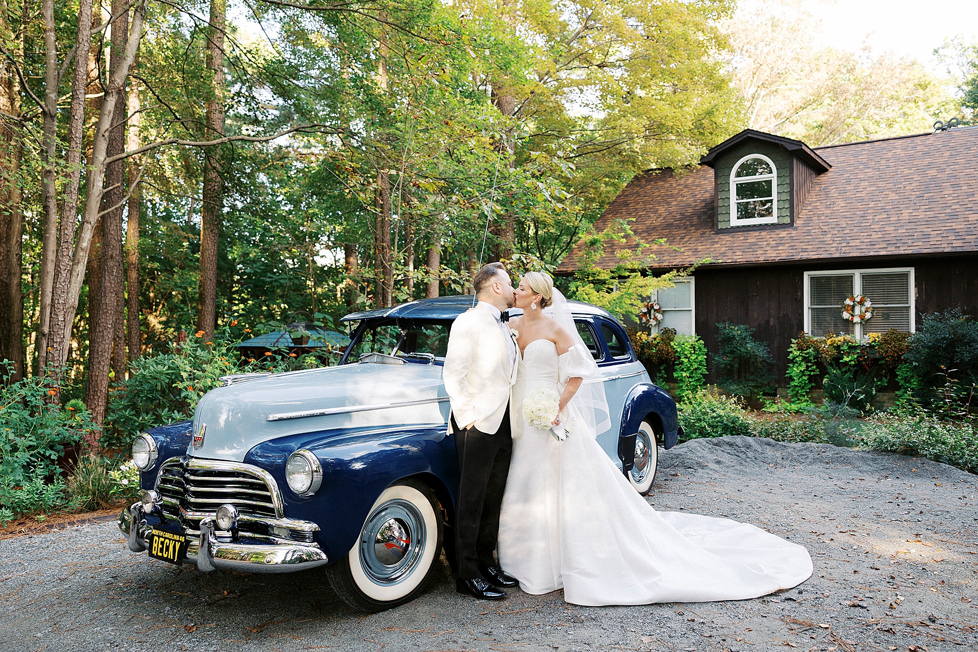 brude and groom kiss in front of car