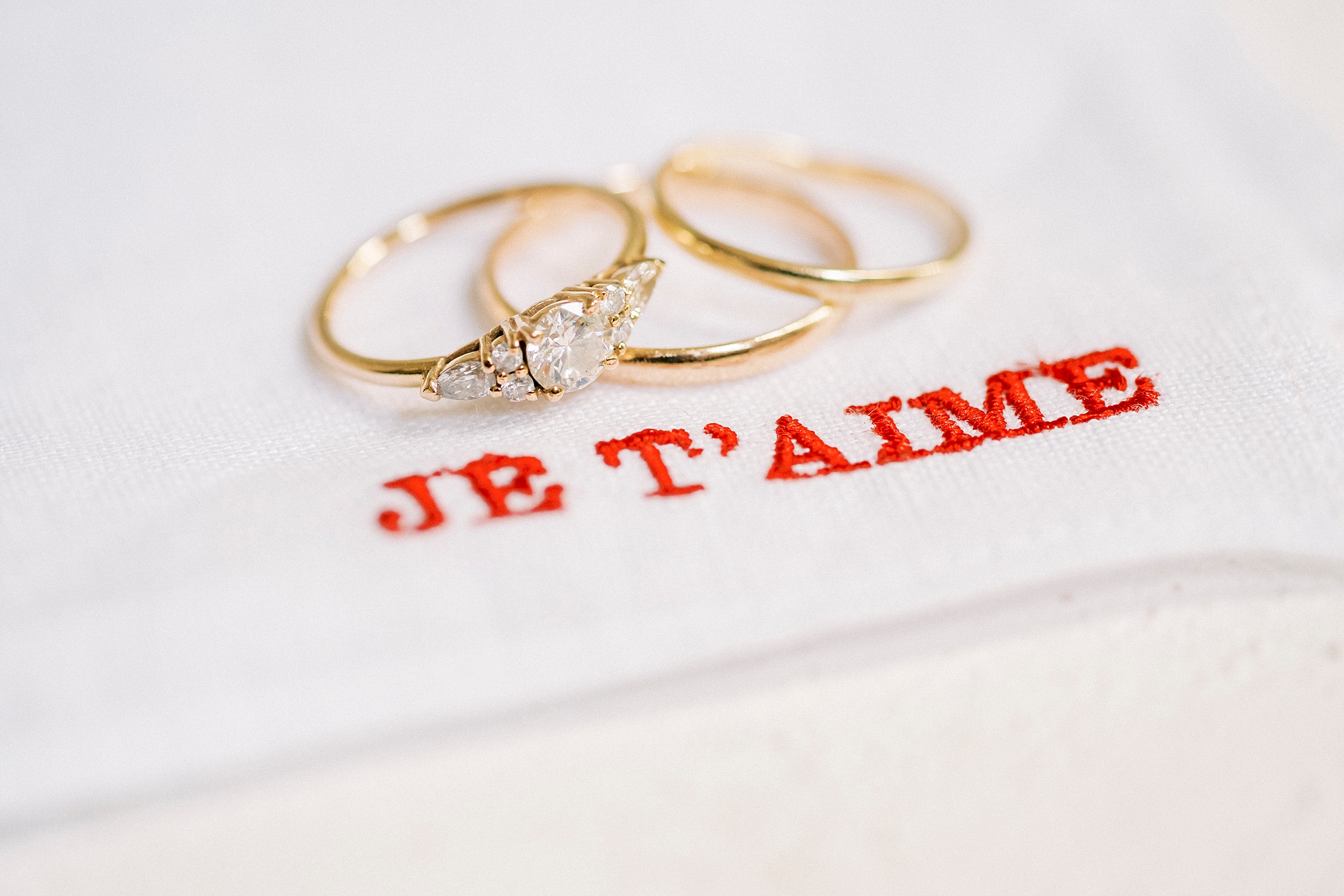 wedding rings on stitched fabric with the words Je taime from French-Inspired Wedding at The Merrimon-Wynne House in Raleigh, NC