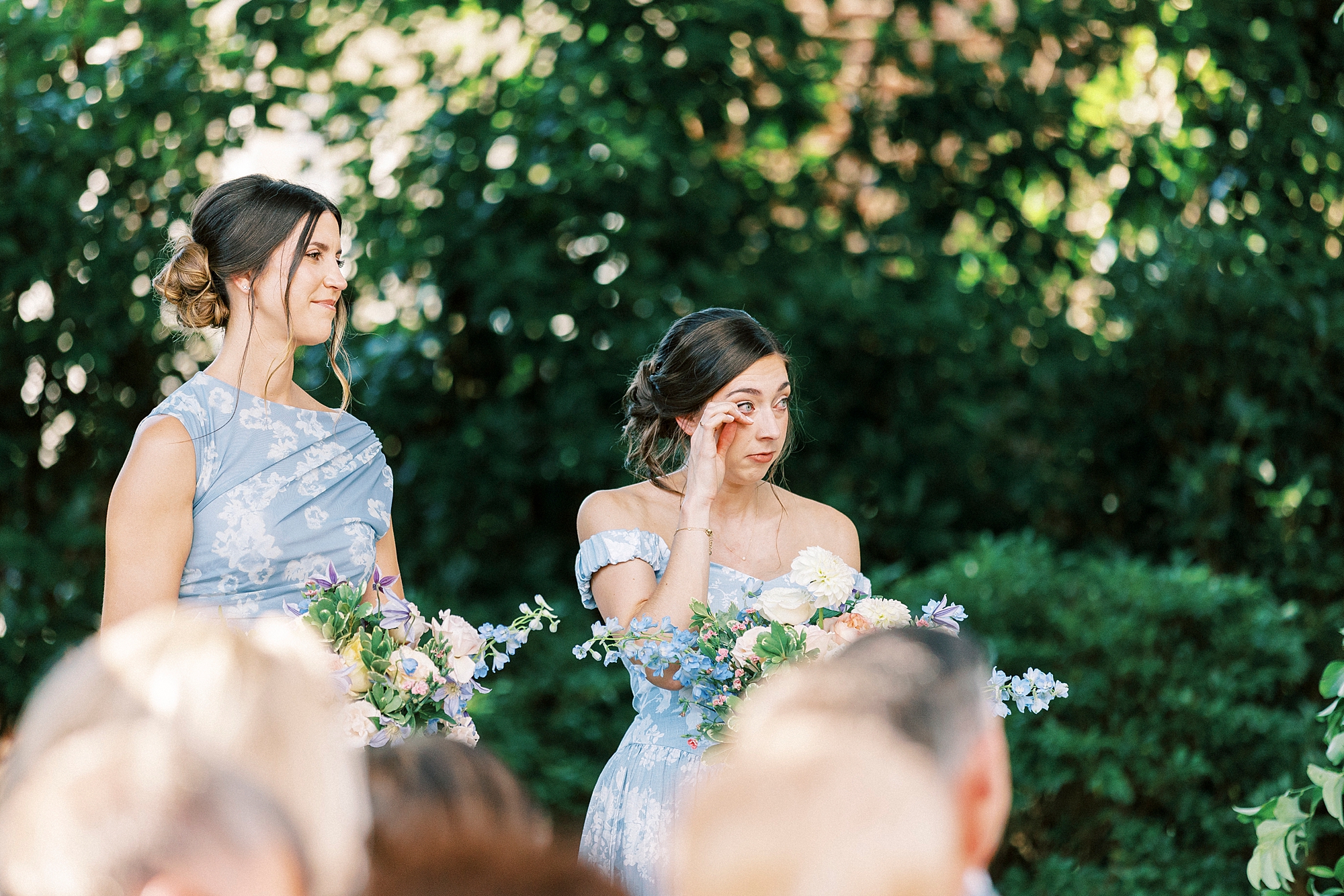bridesmaids wipe away tears during ceremony 