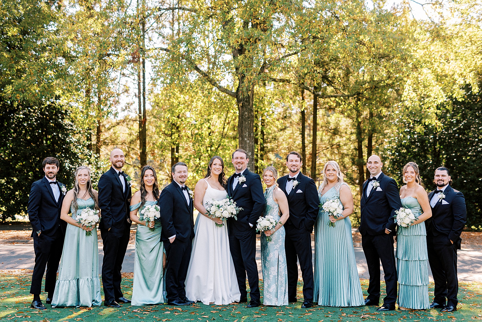 bridesmaids in light teal dresses with groomsmen in tuxes 