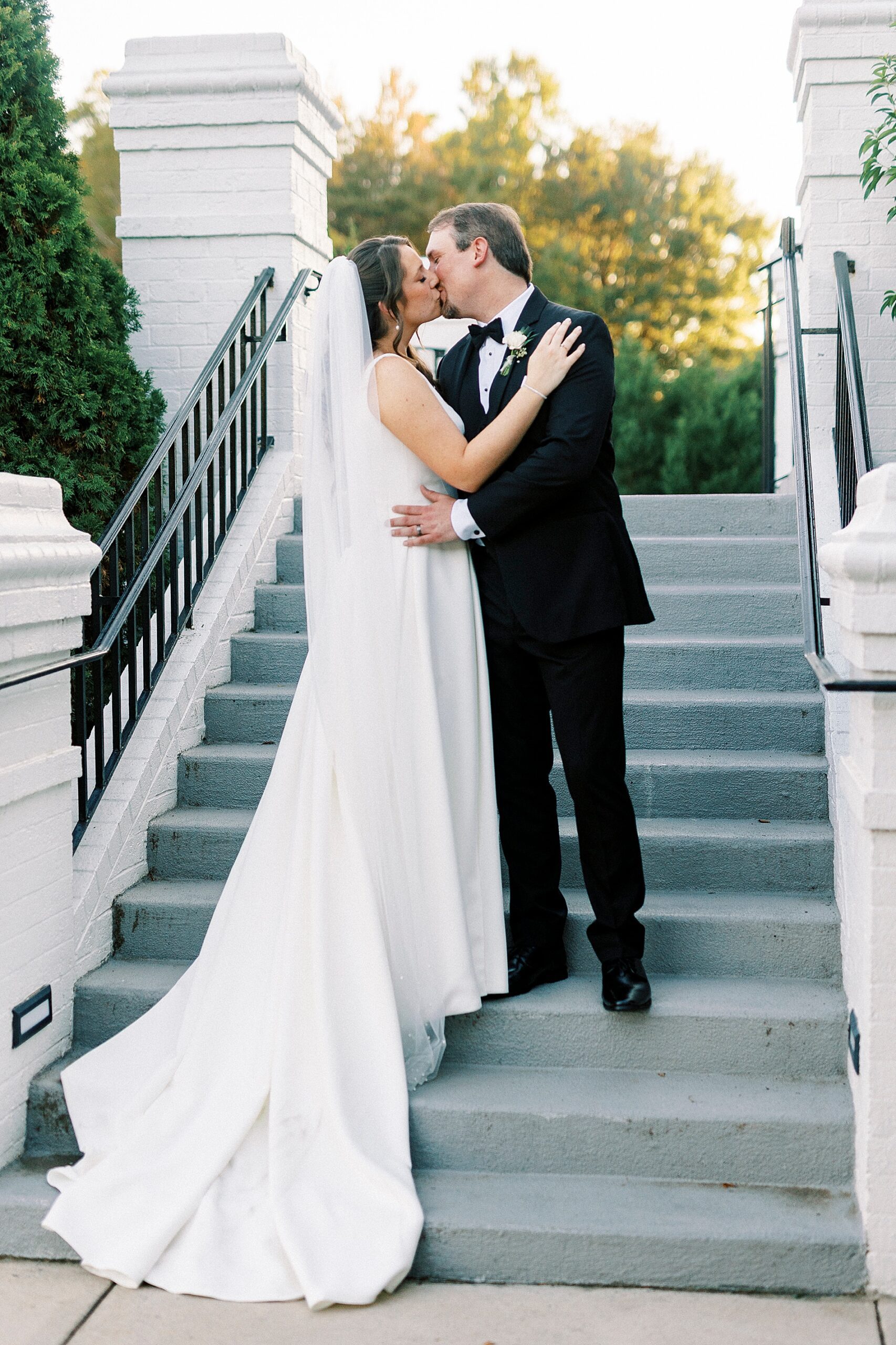 newlyweds kiss on stairs of Providence Country Club  