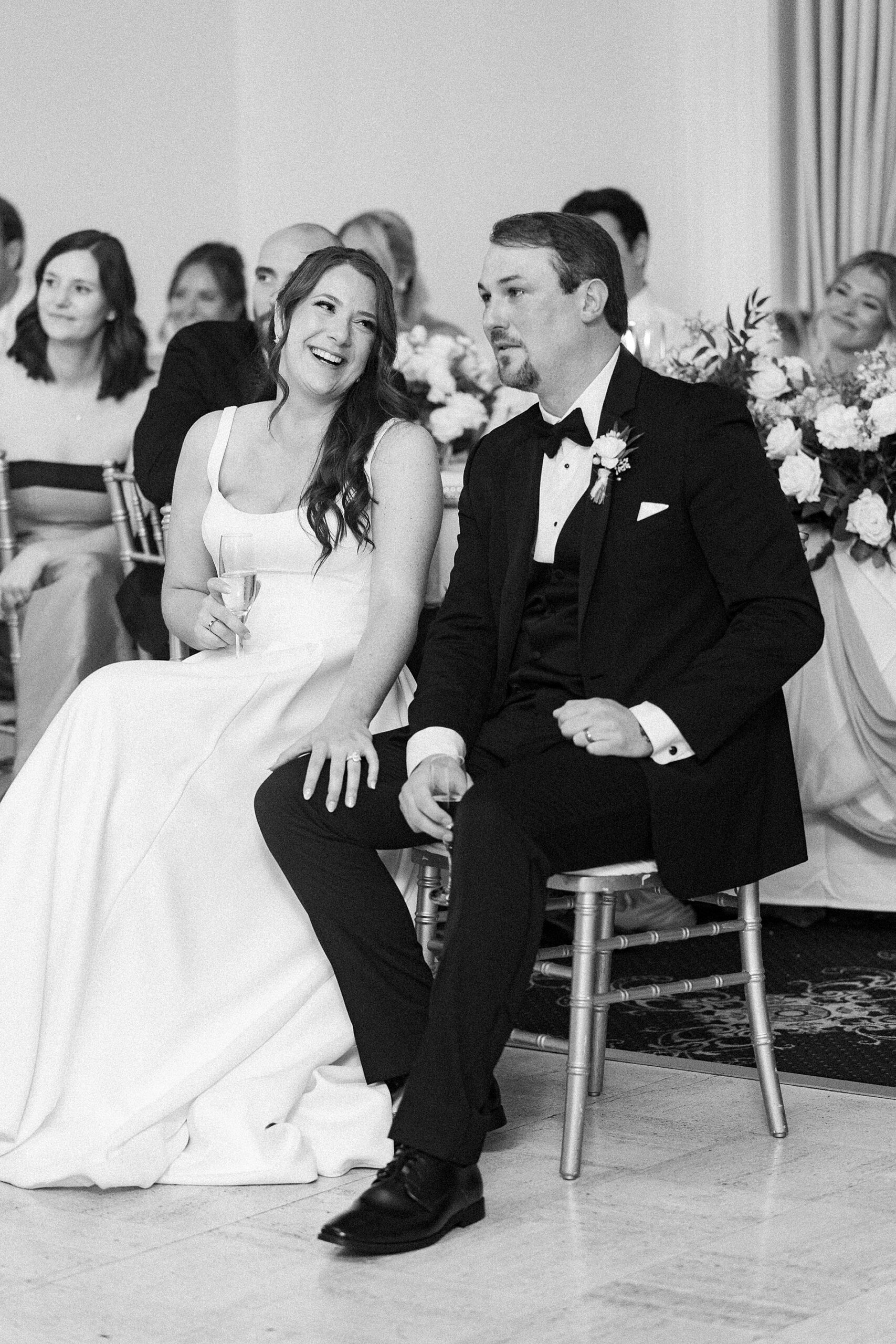 candid wedding portraits of bride and groom listening to toasts 