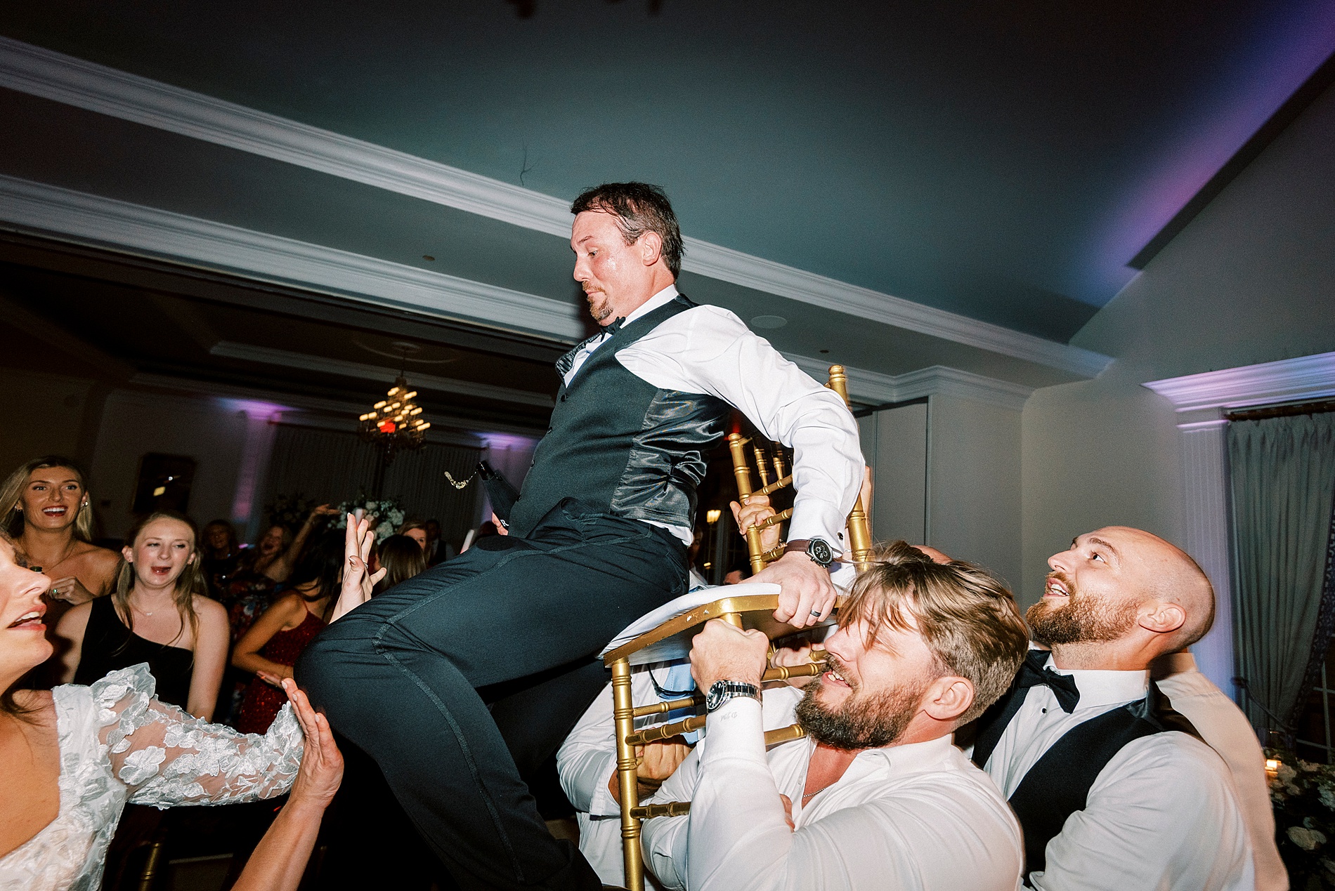 guests lift groom up on chair
