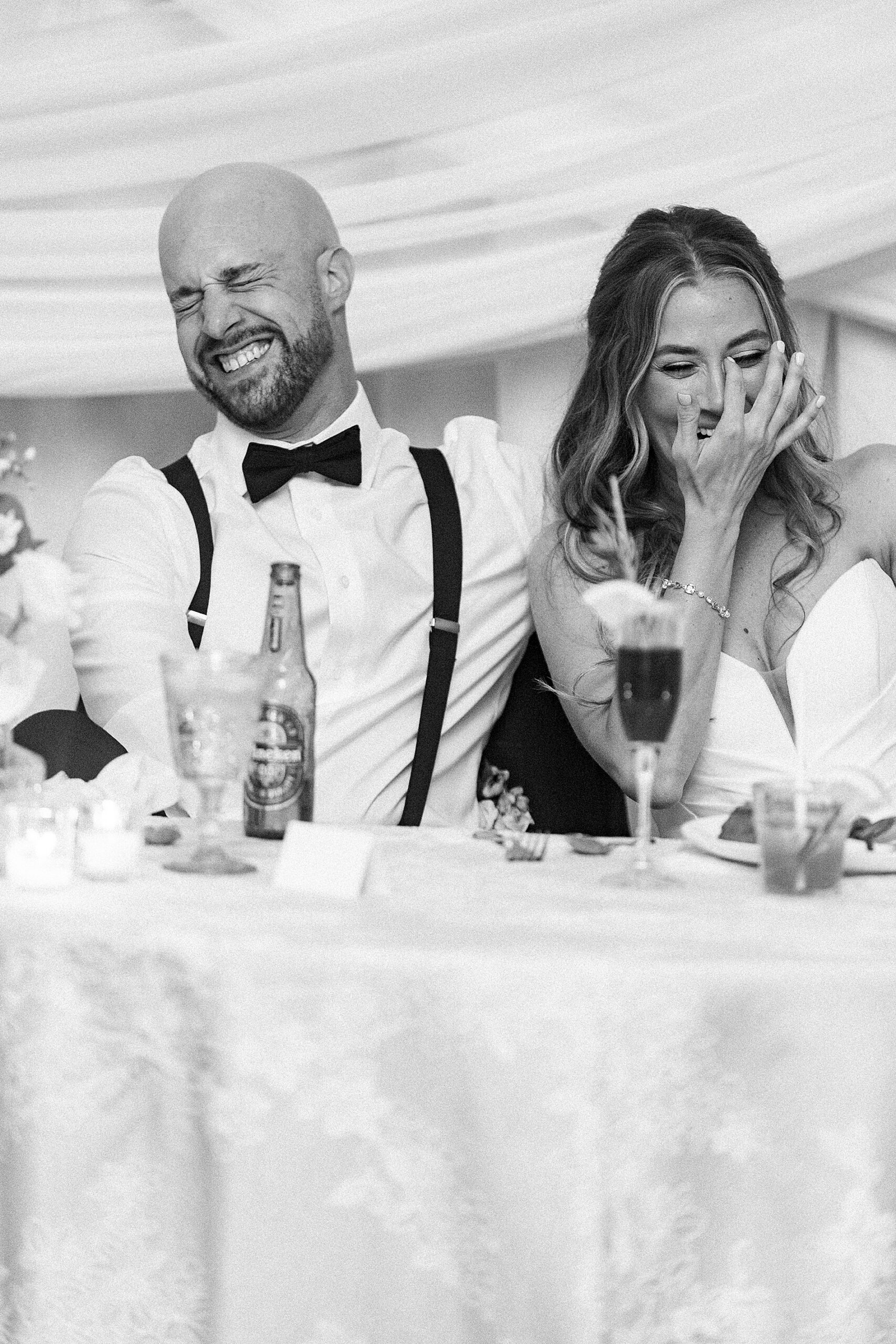 couple laugh during wedding speeches