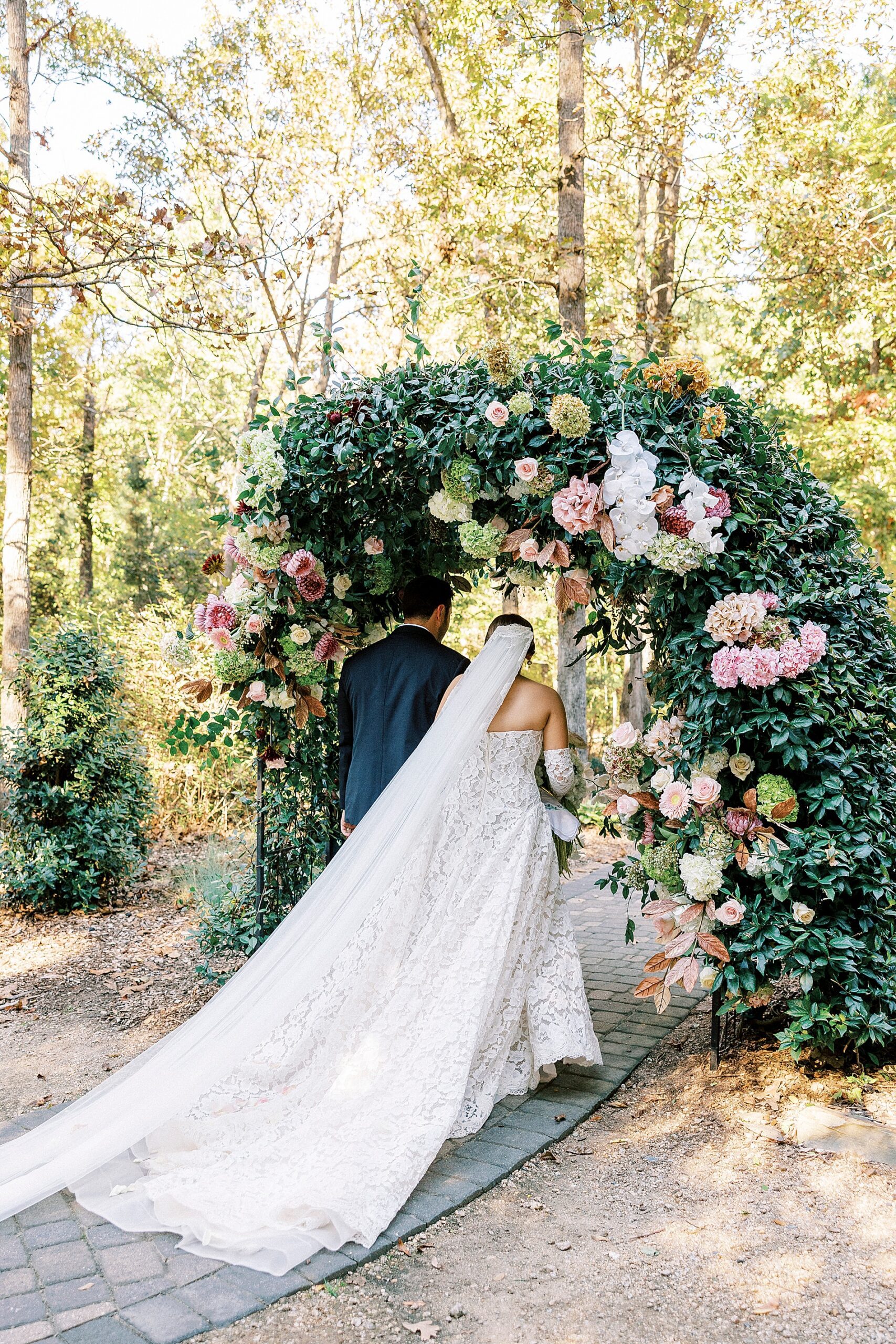 bride and groom walk under floral arch after ceremony 