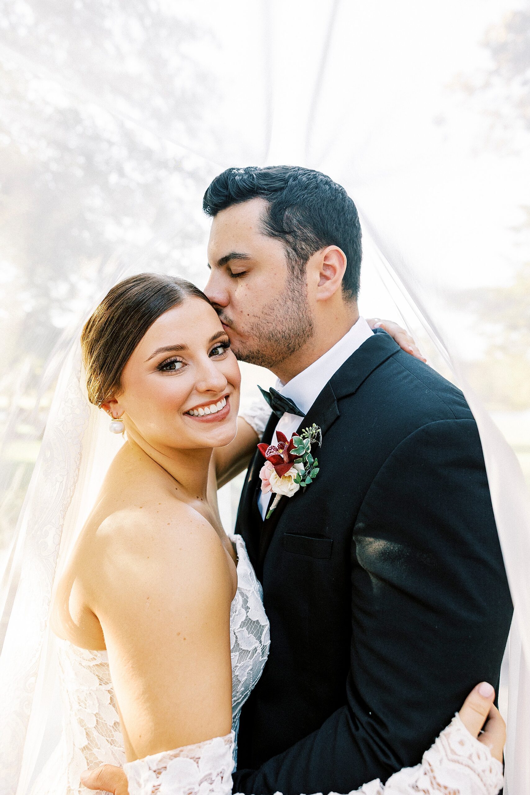 groom kisses bride on her head