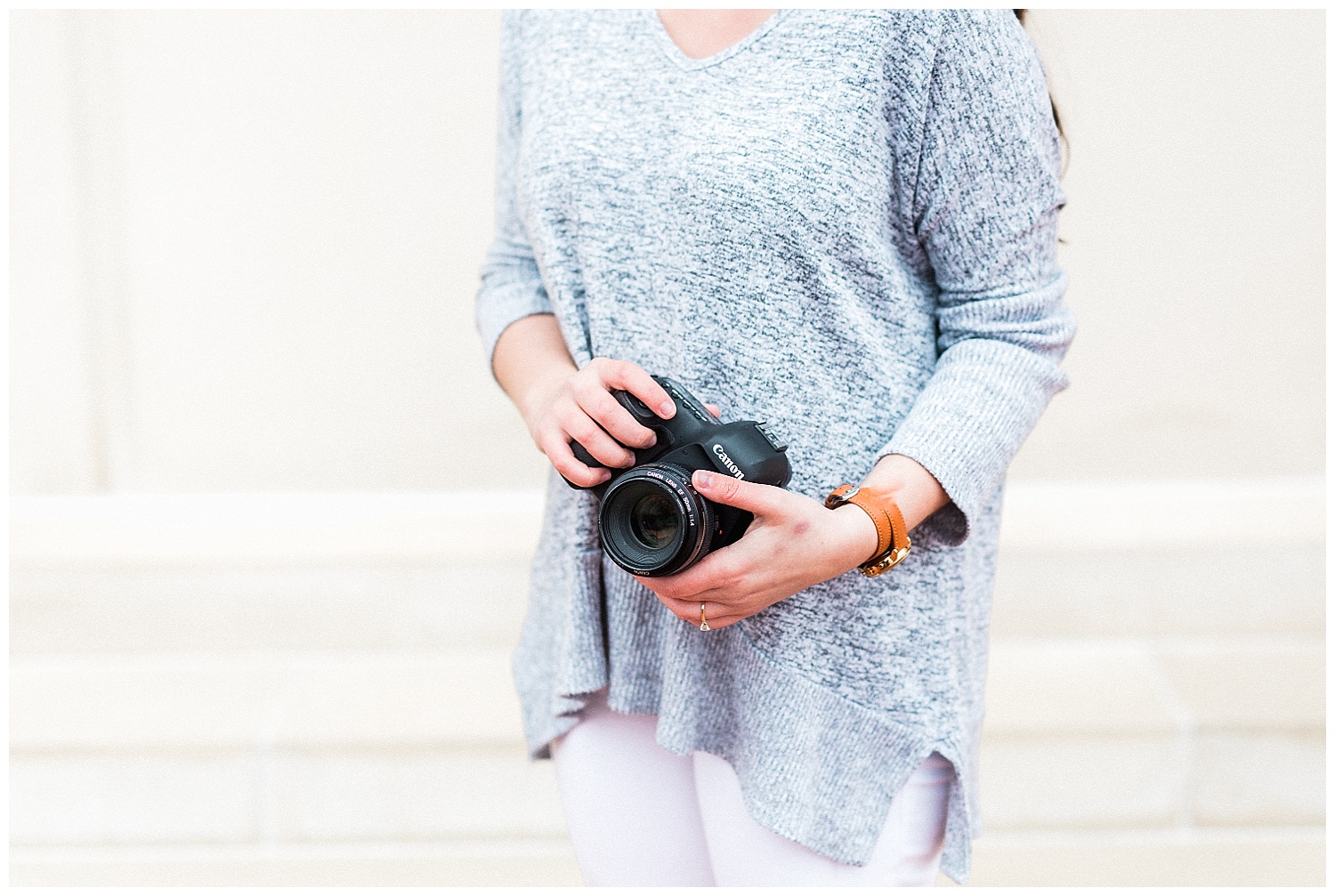 girl holding camera with grey sweater